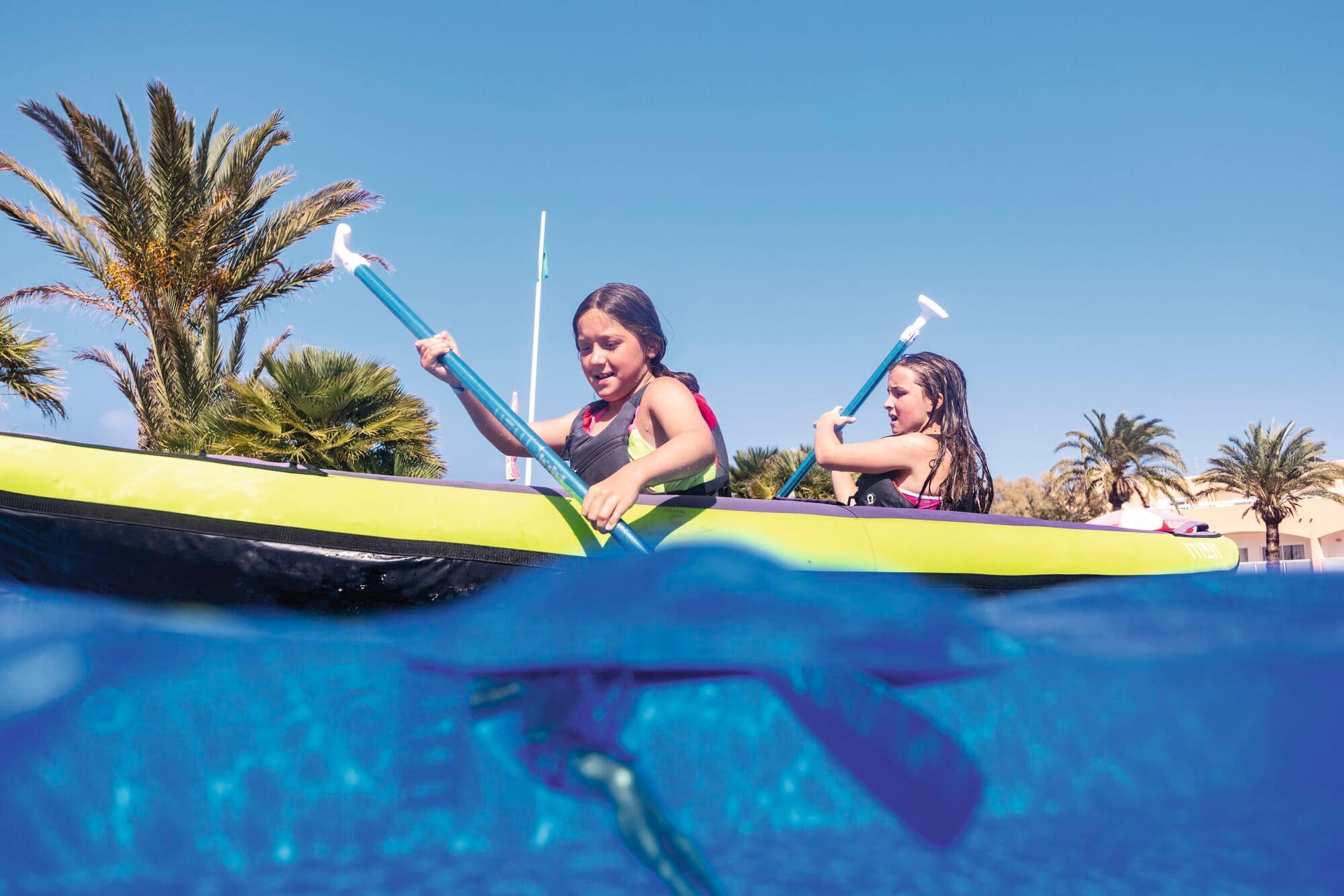 Two girls kayaking in a pool.