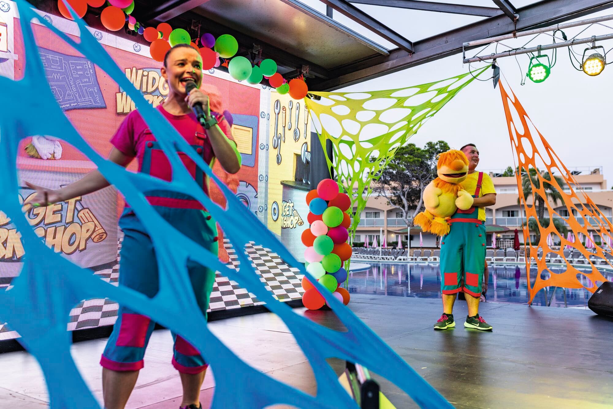 Entertainment team wearing carnival-style feathered costumes on stage in the evening.