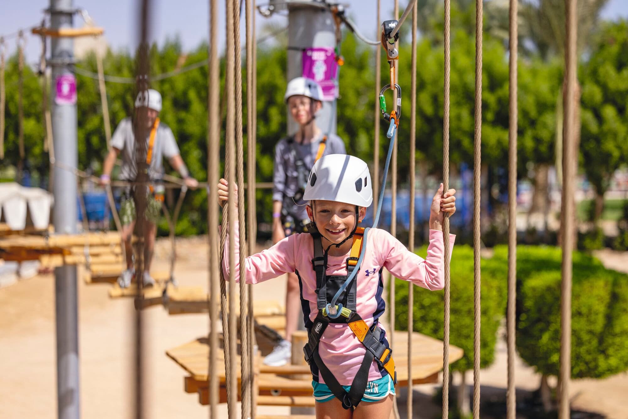 Children in climbing gear on the Aerial Adventure course.