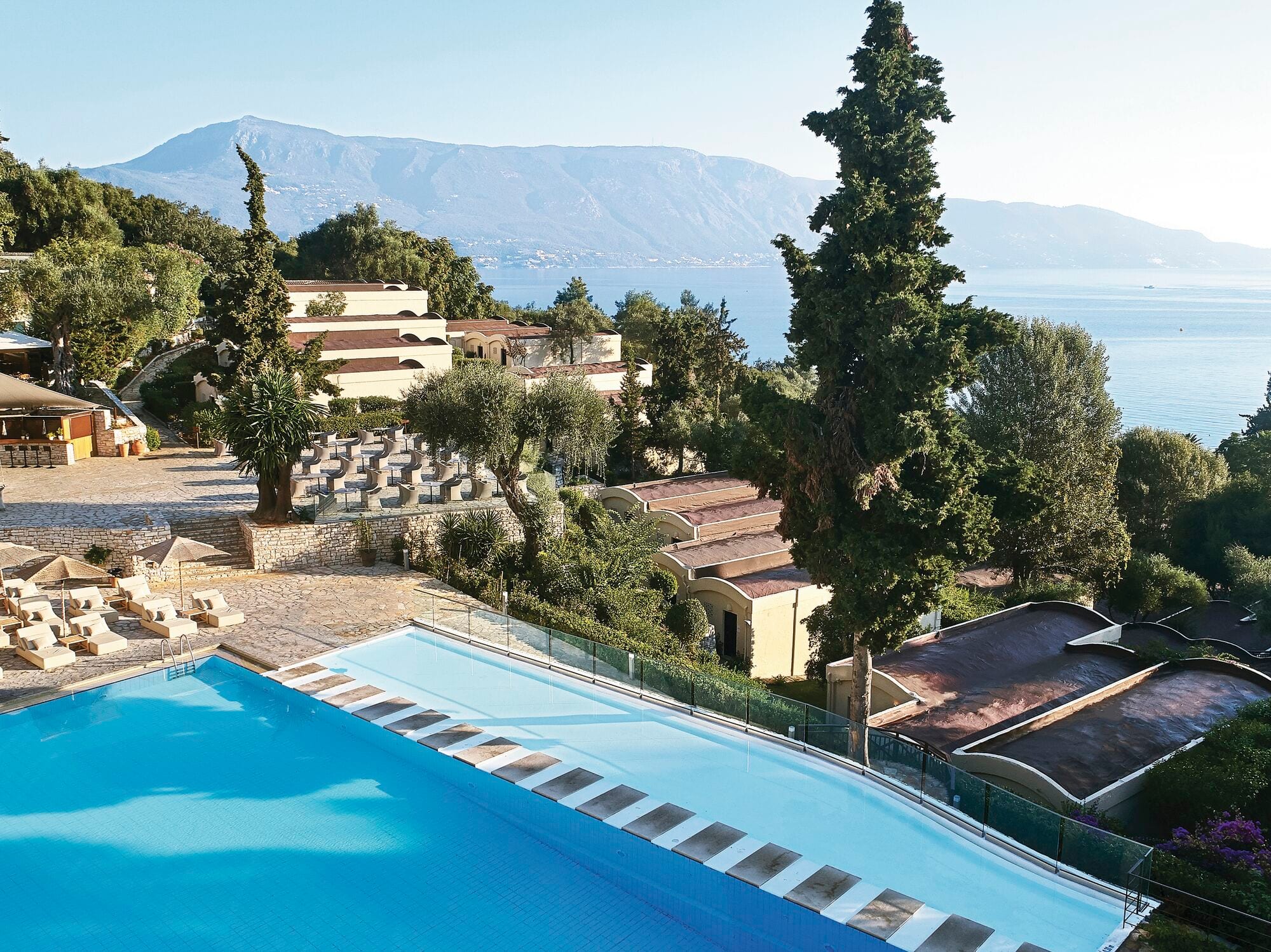 The pool at the Grecotel Lux Me Daphnila Bay resort in Corfu, surrounded by sea and green mountains.