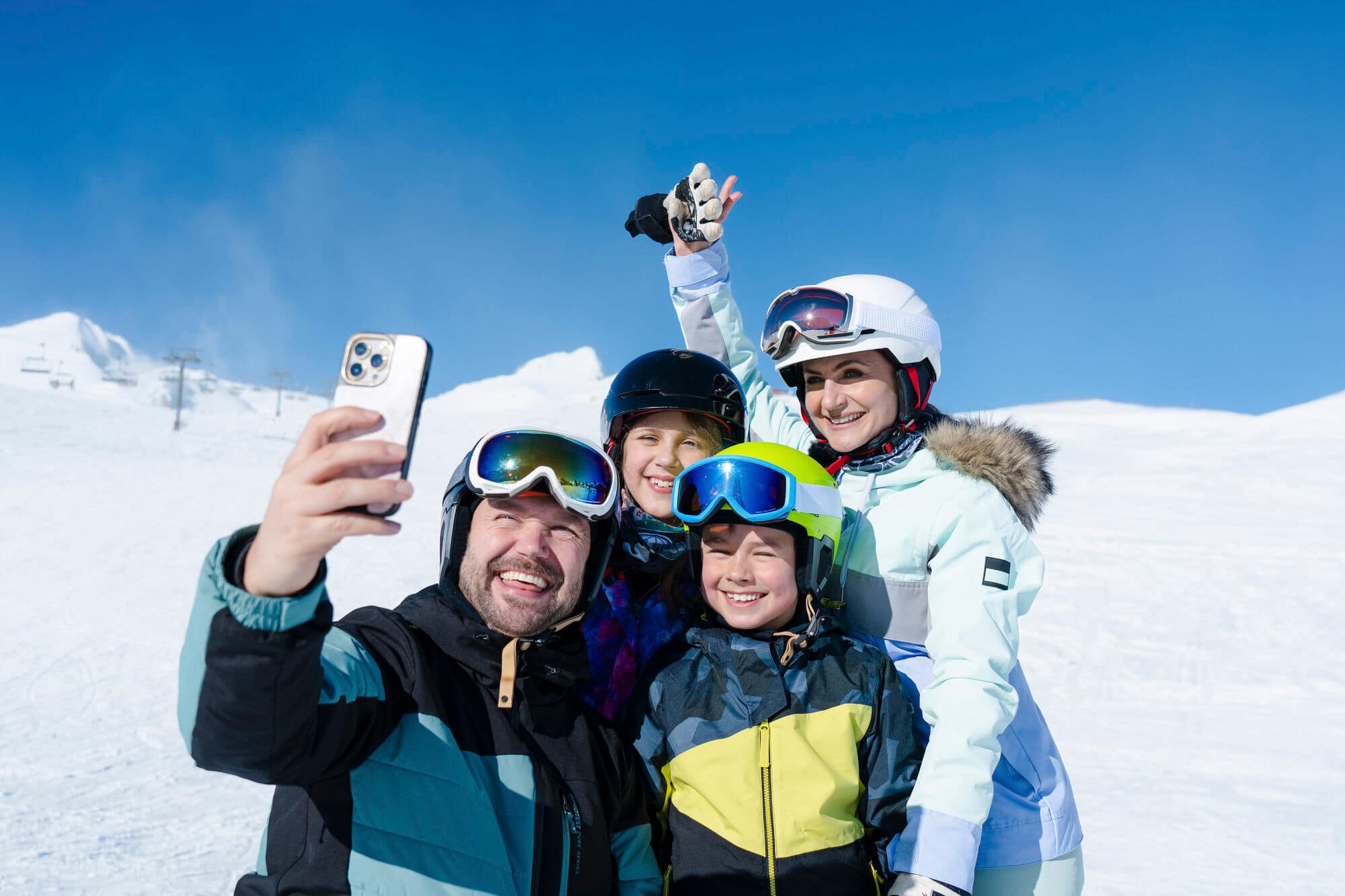 Two adults and two children in ski gear taking a selfie.