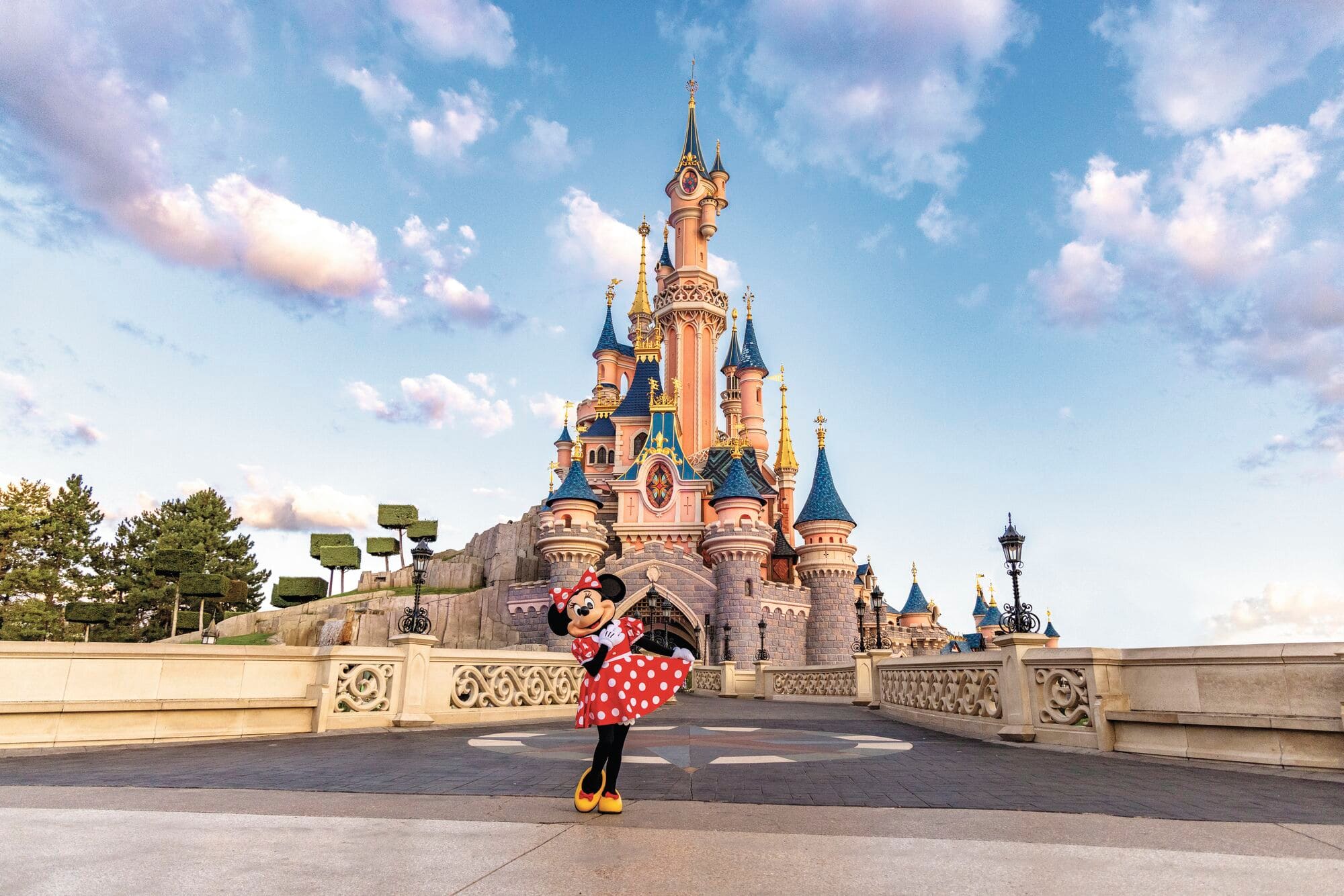 Minnie Mouse in front of the Sleeping Beauty Castle.