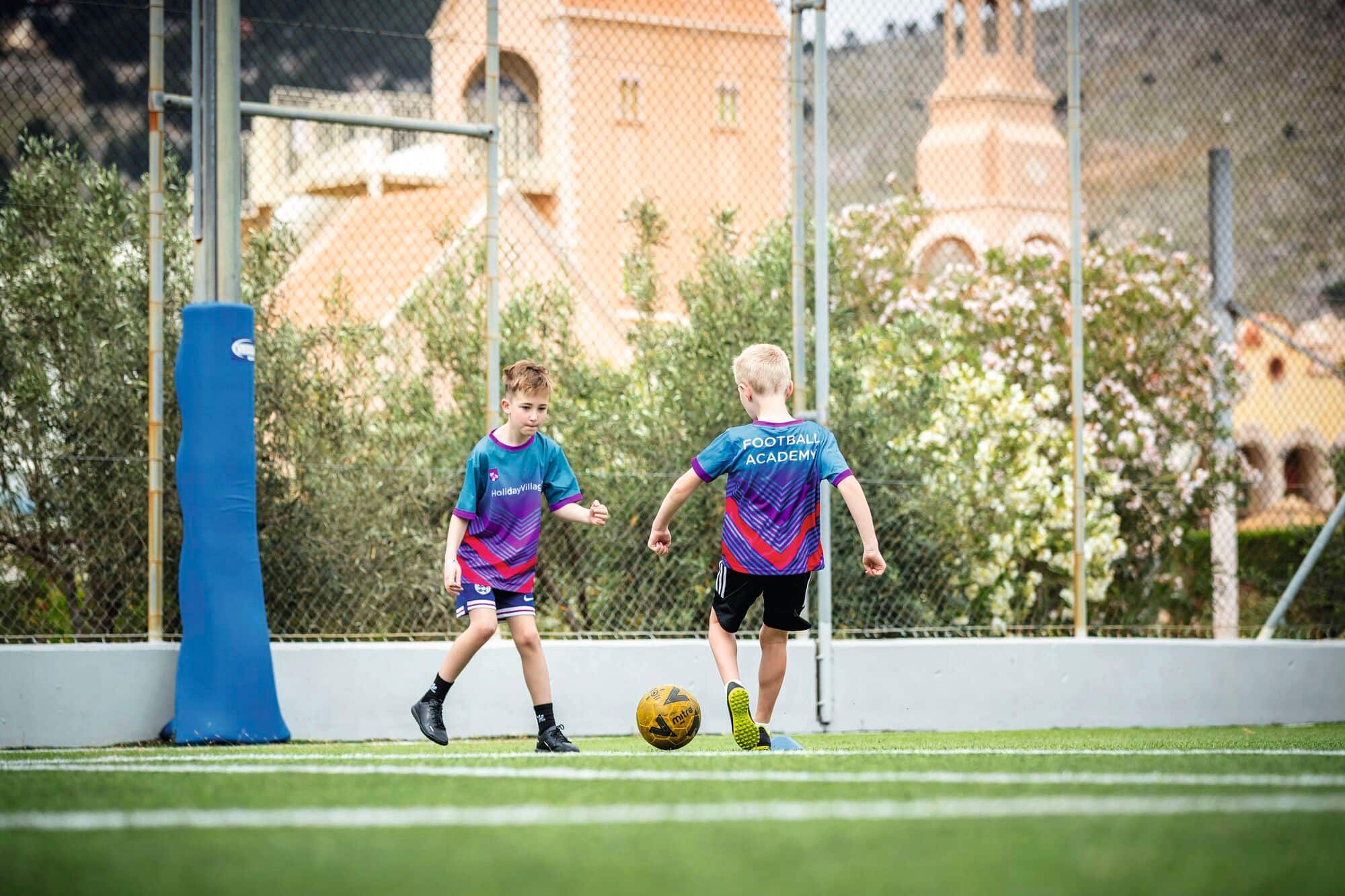 Two children kicking a football to eachother.