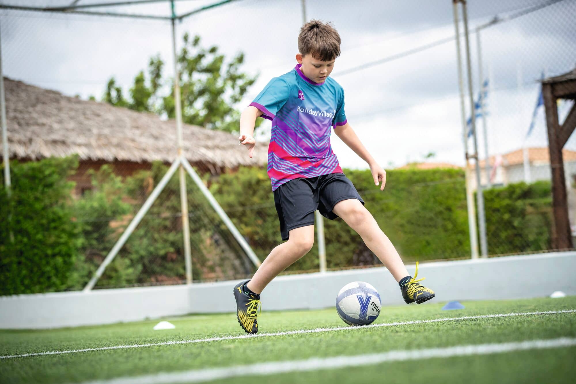 A football coach doing kick-ups with a yellow football.