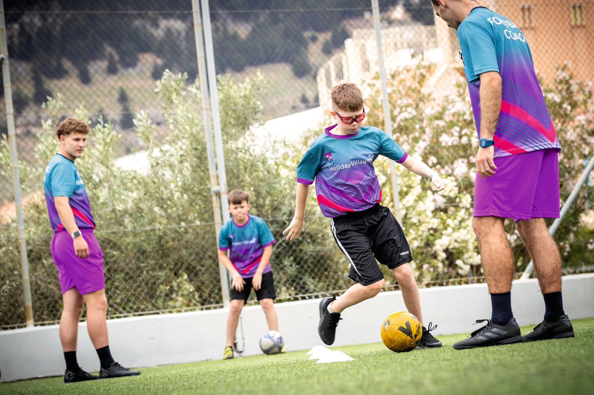 A boy kicking a football between cones.