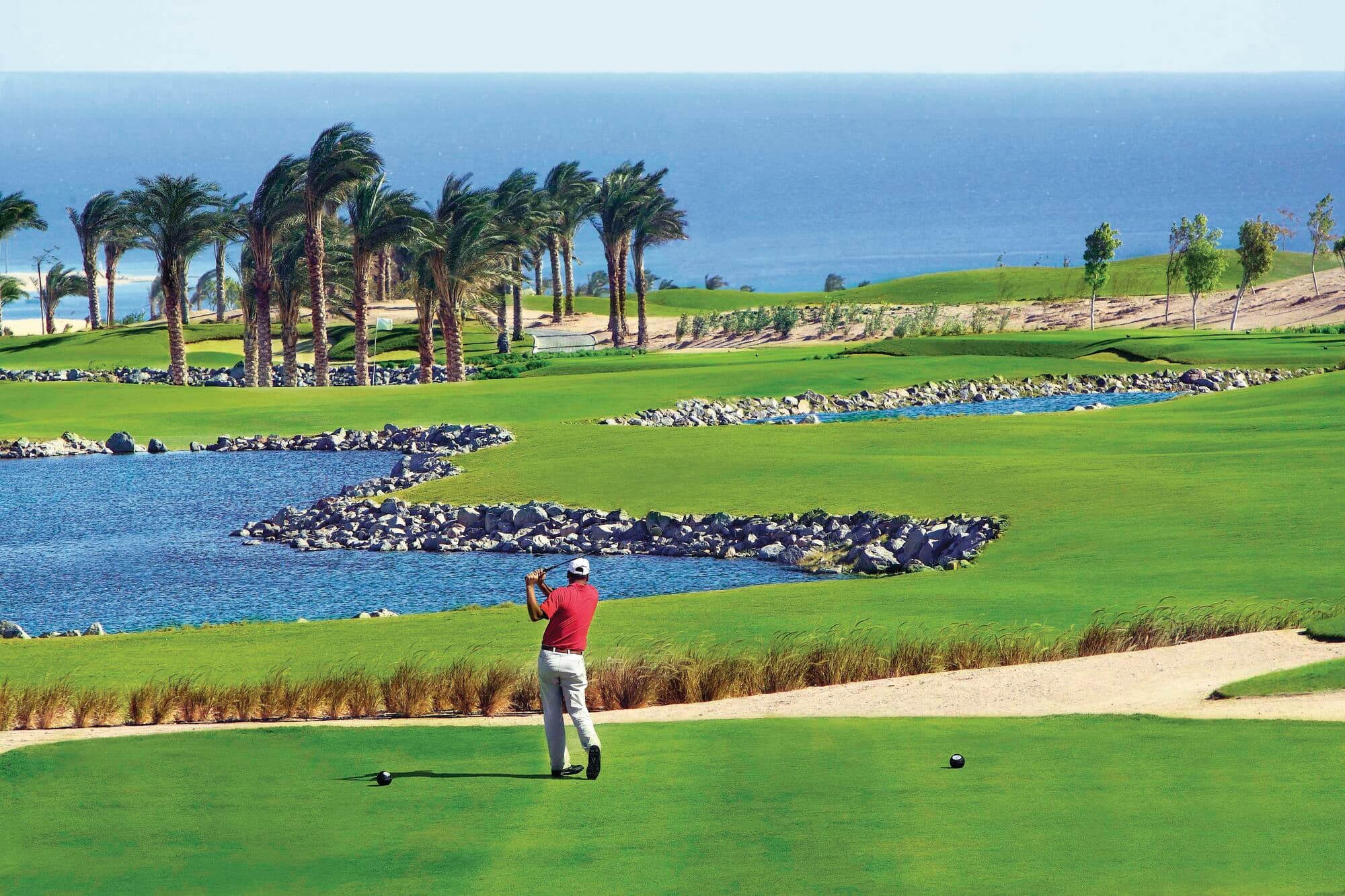A golfer is mid-swing at Madinat Makadi golf course.