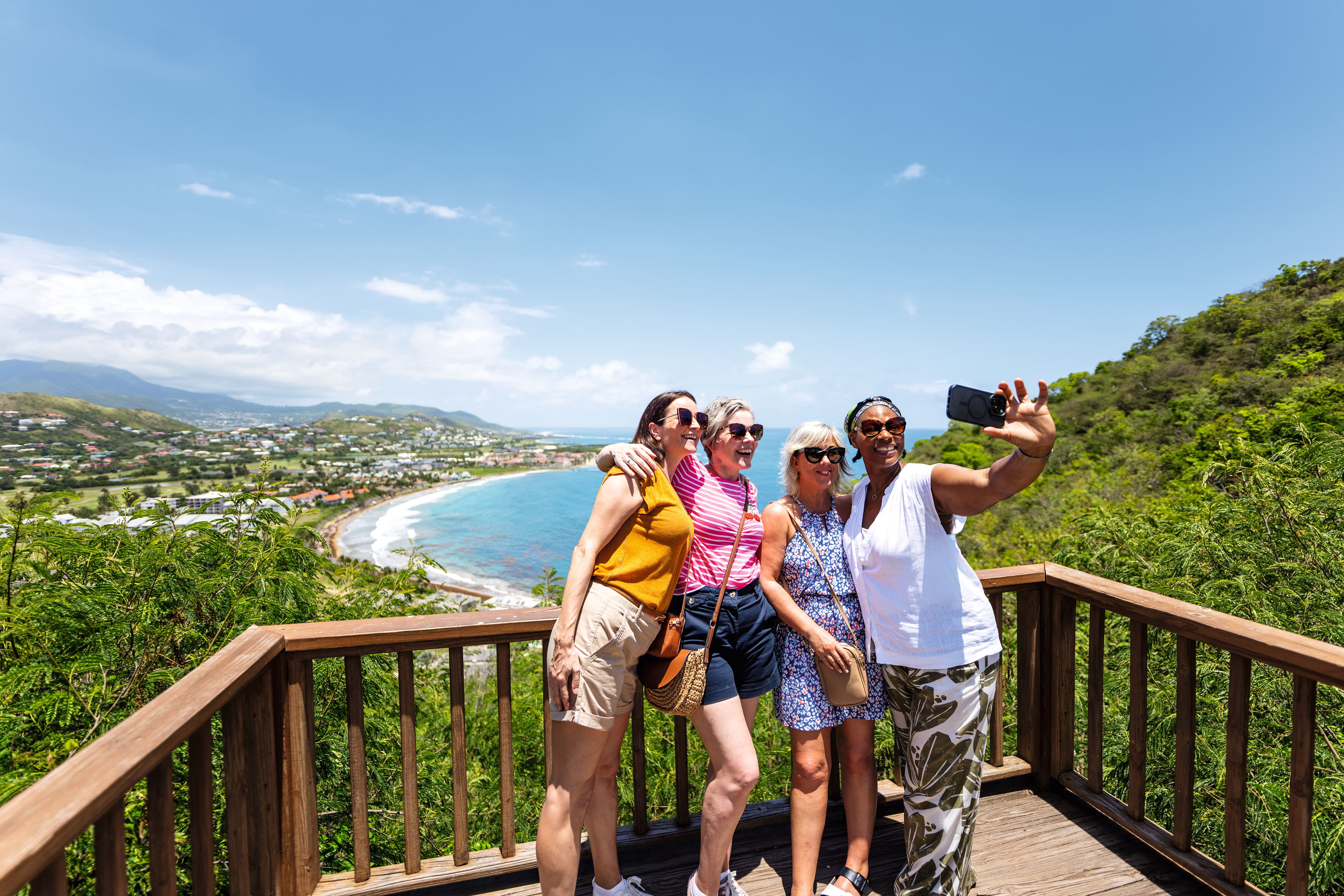 Four friends take a selfie overlooking a seaside town.