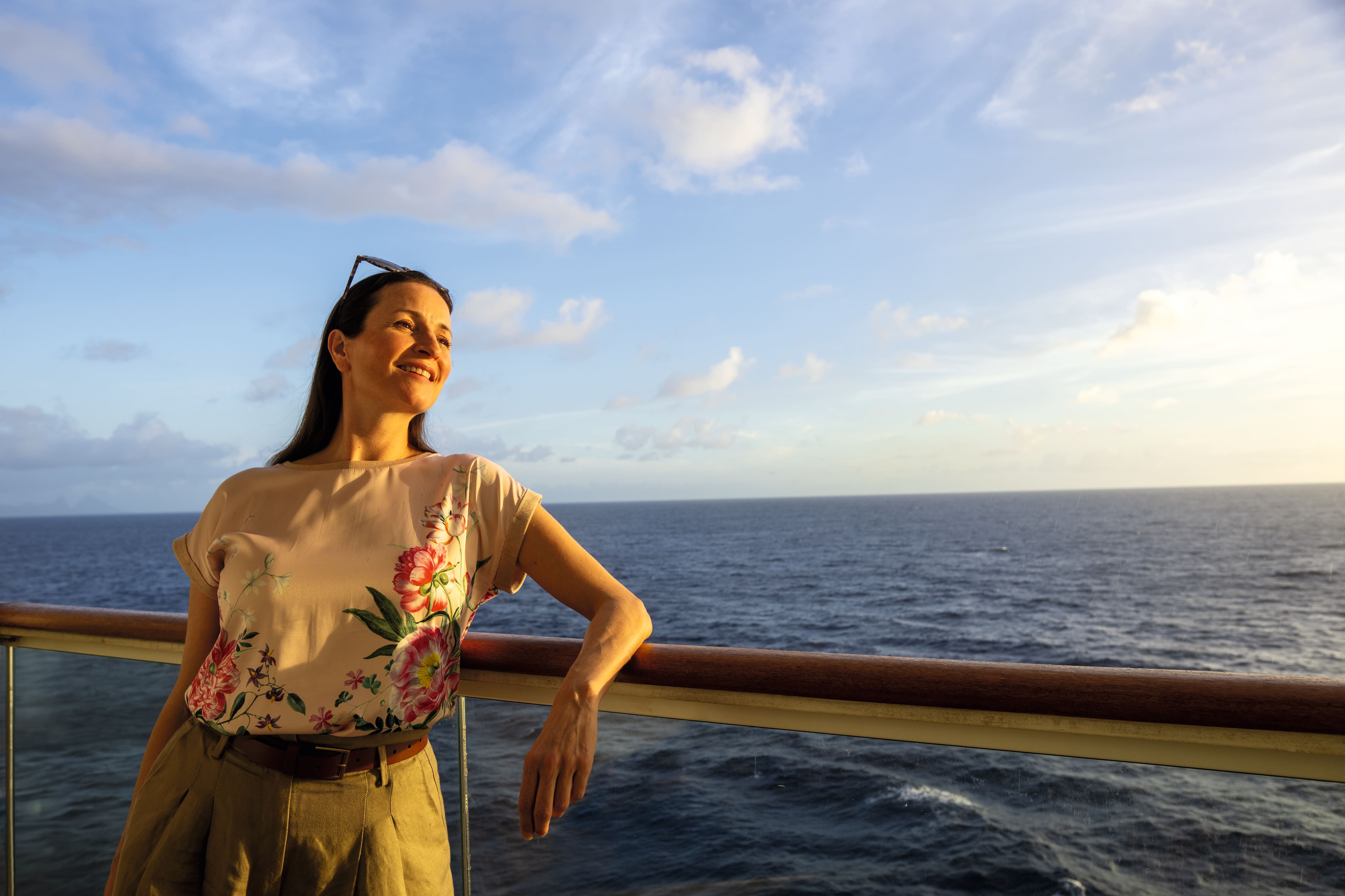 A person leans on the railing of a ship looking out to sea.