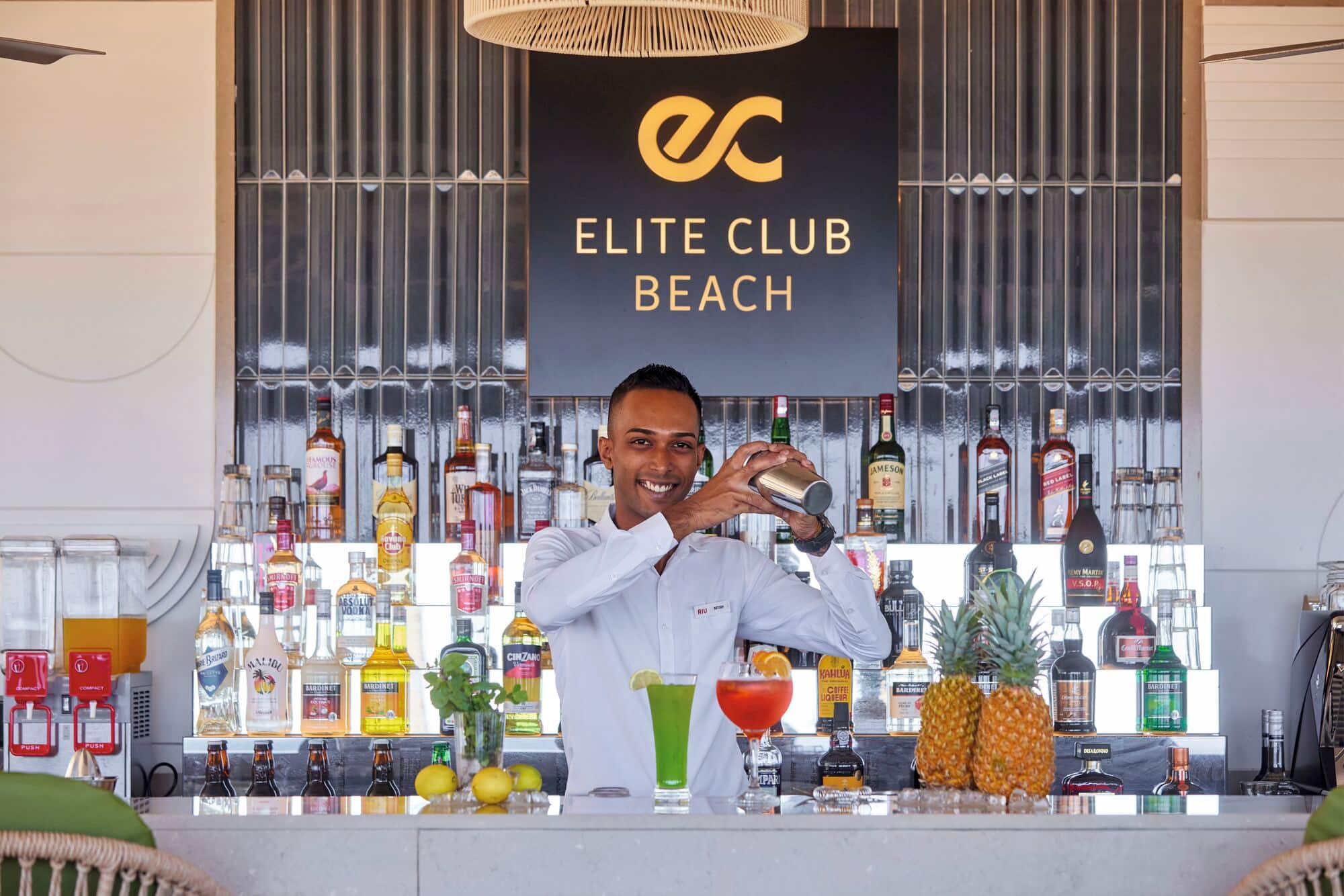 A bartender mixing cocktails at an Elite Club bar.