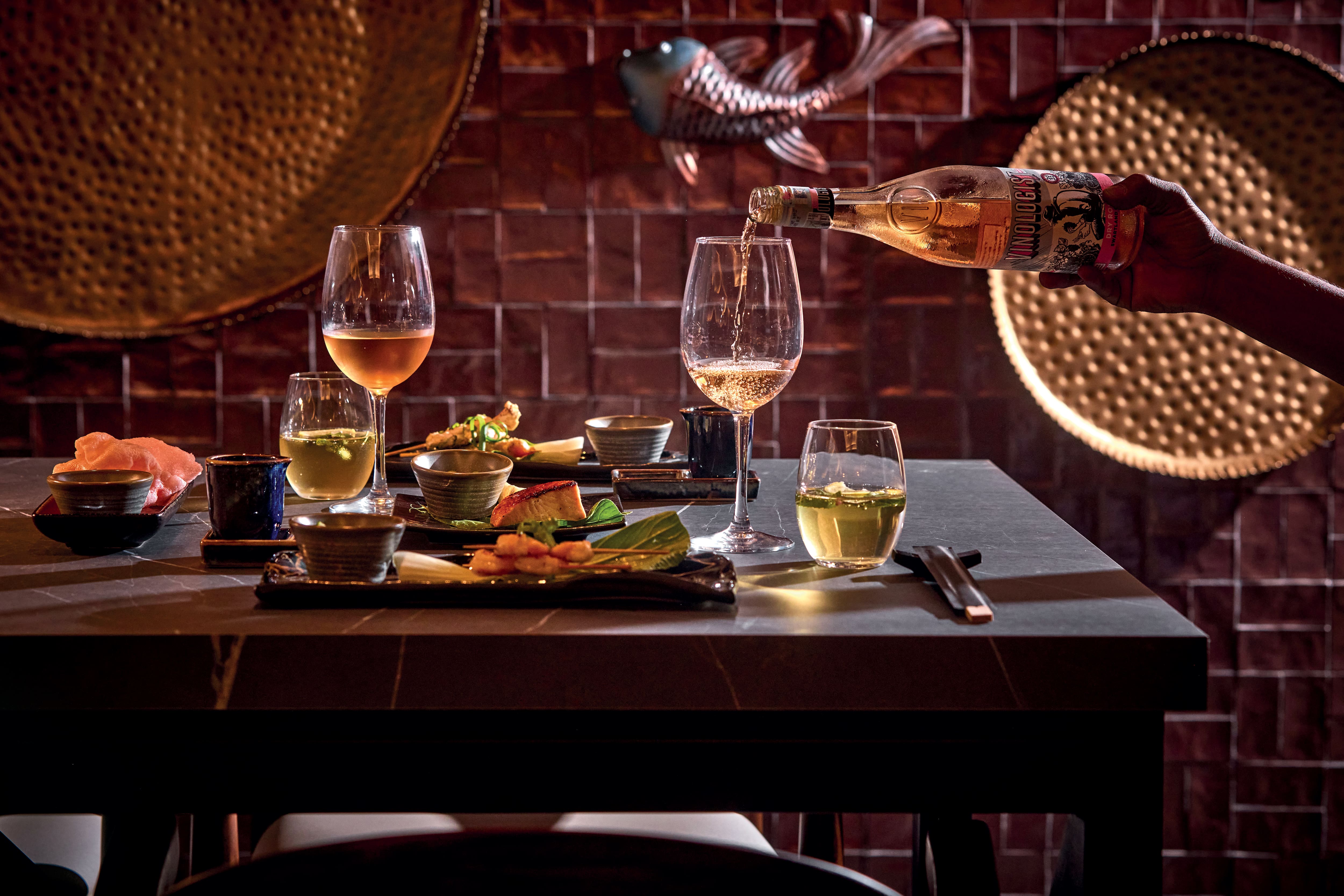 Wine being poured into glasses at a dining table.