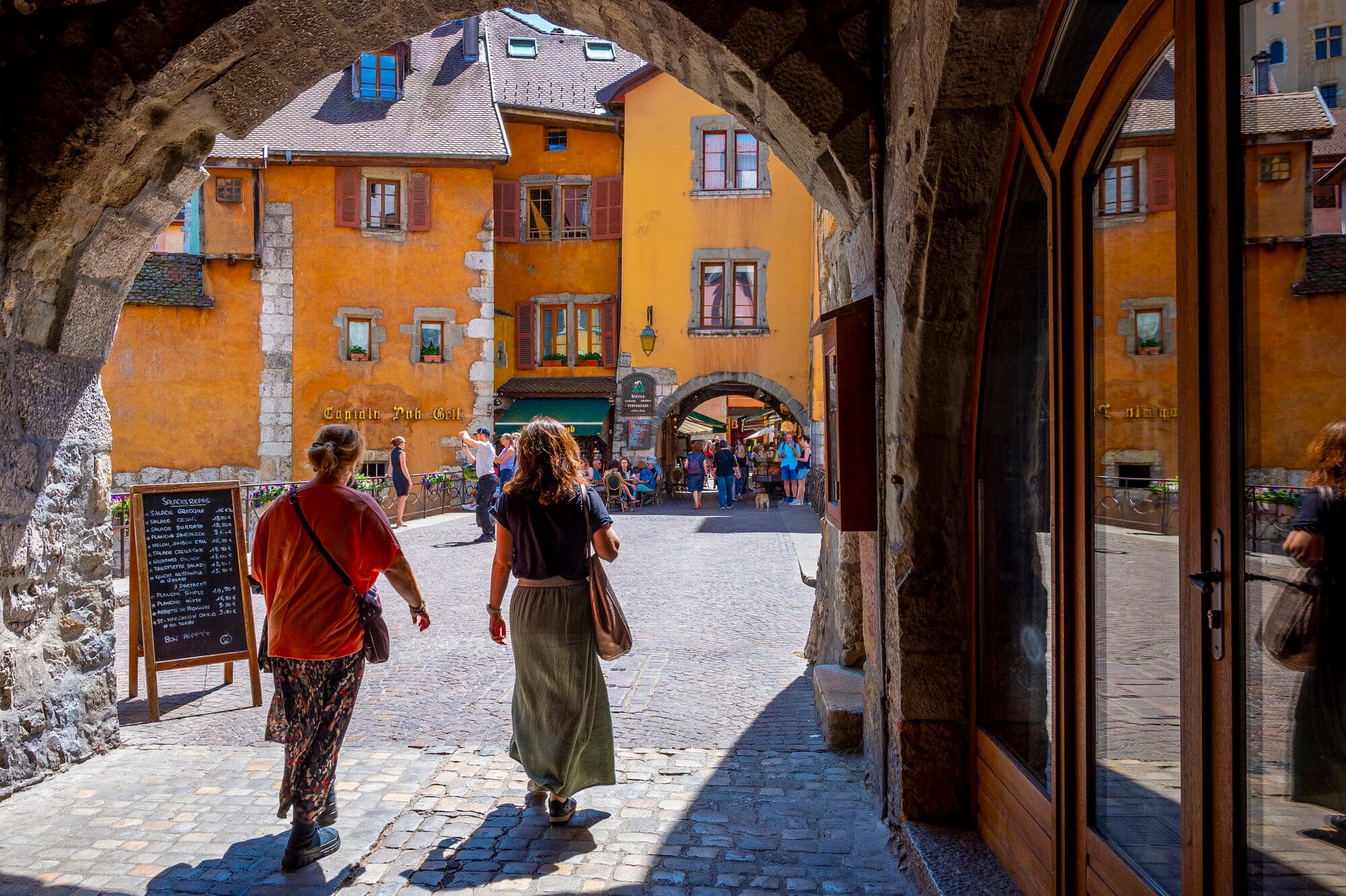 Two people walking through an archway in the centre of Annecy. 