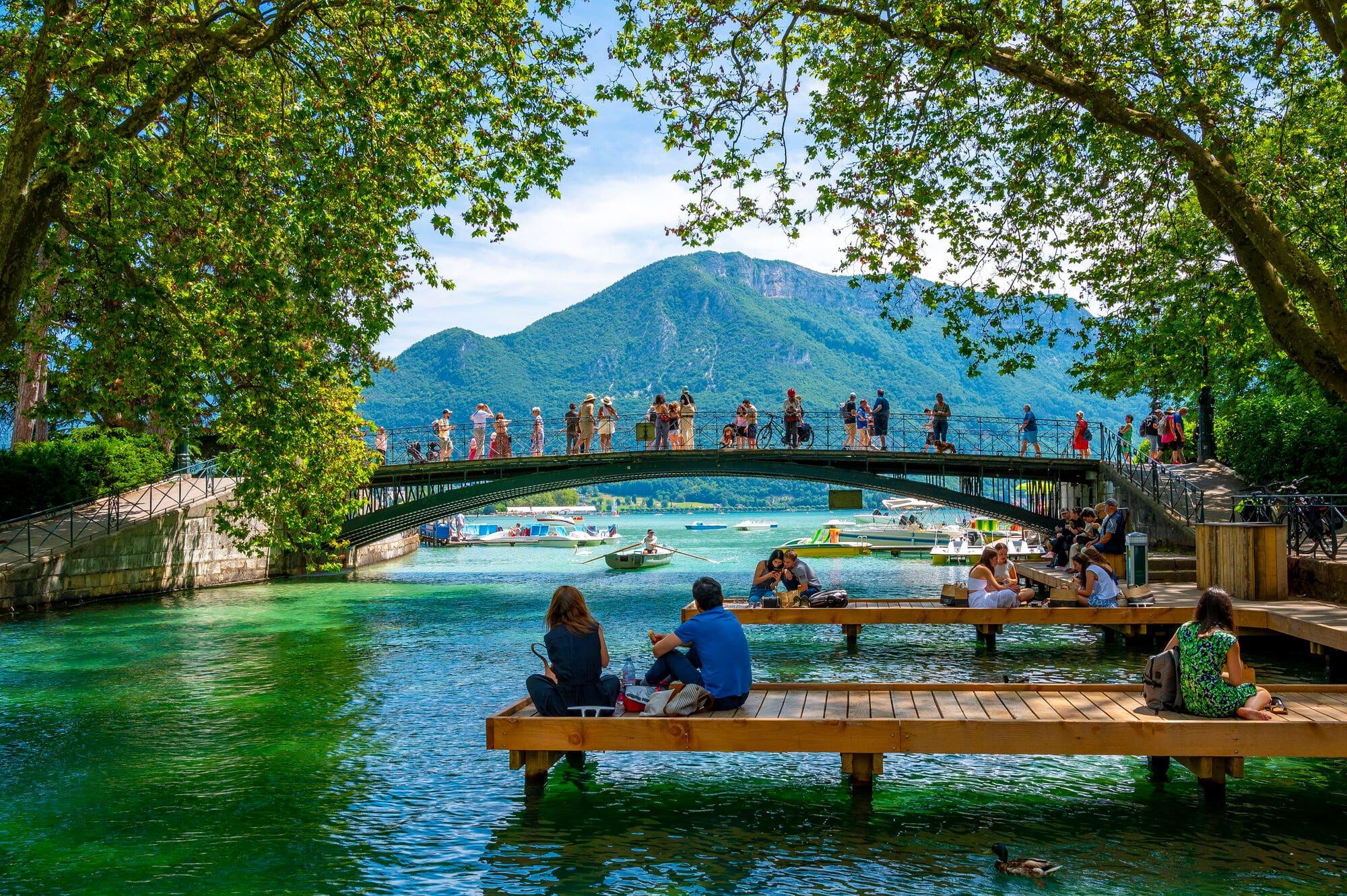 Canals in the centre of Annecy town. The canal flows into Lake Annecy. A bridge crosses the canal. 