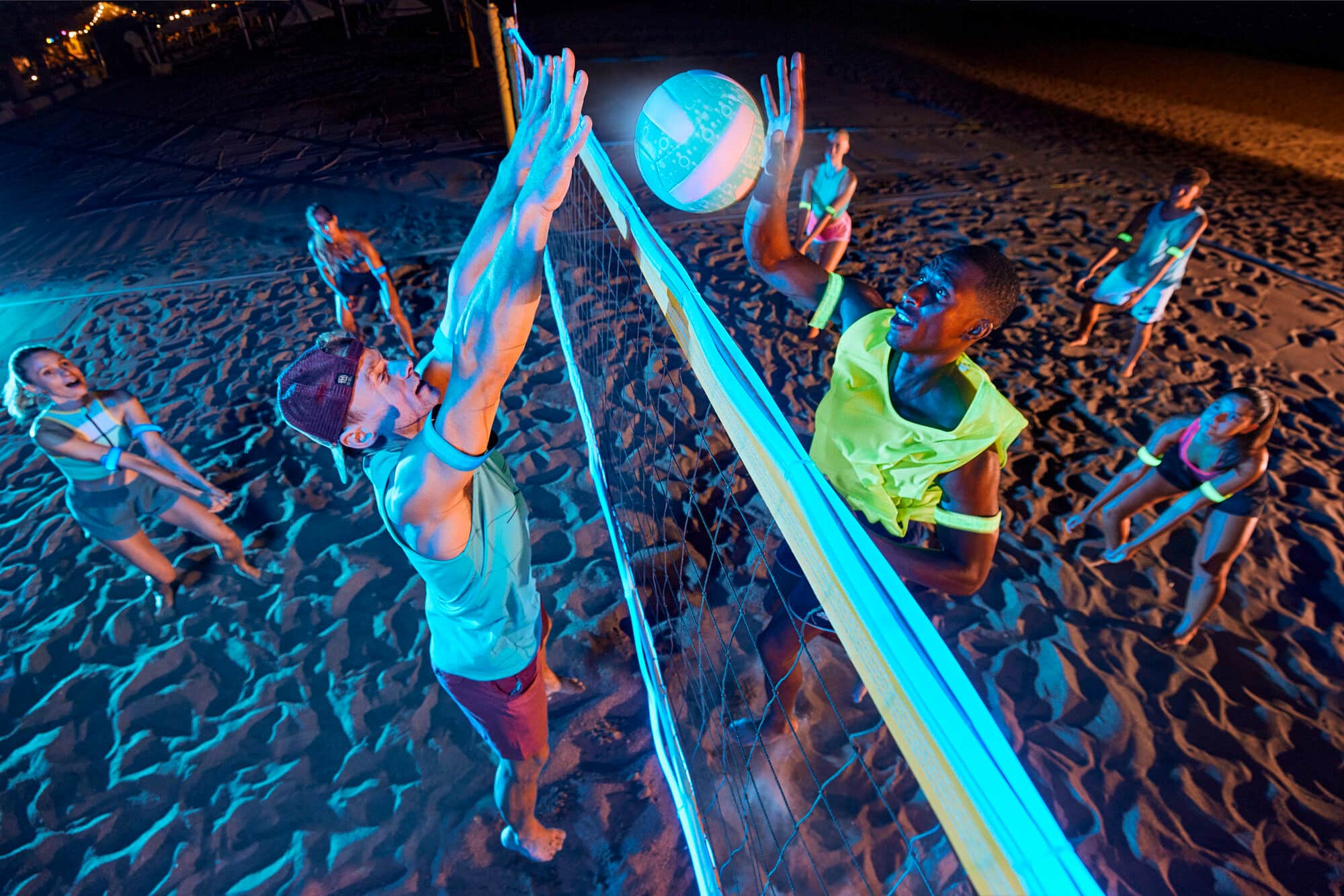 A group of people playing night volleyball.