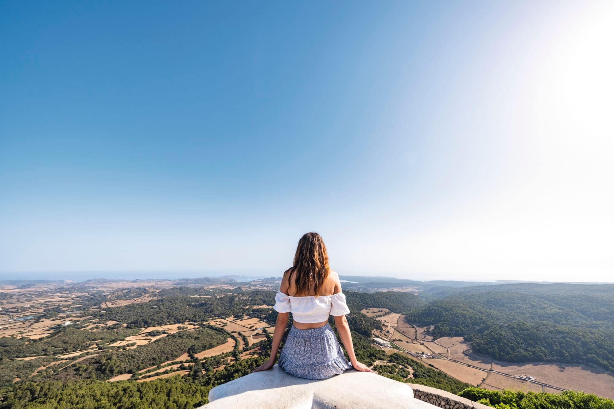 Woman sitting and looking out over countryside landscape.