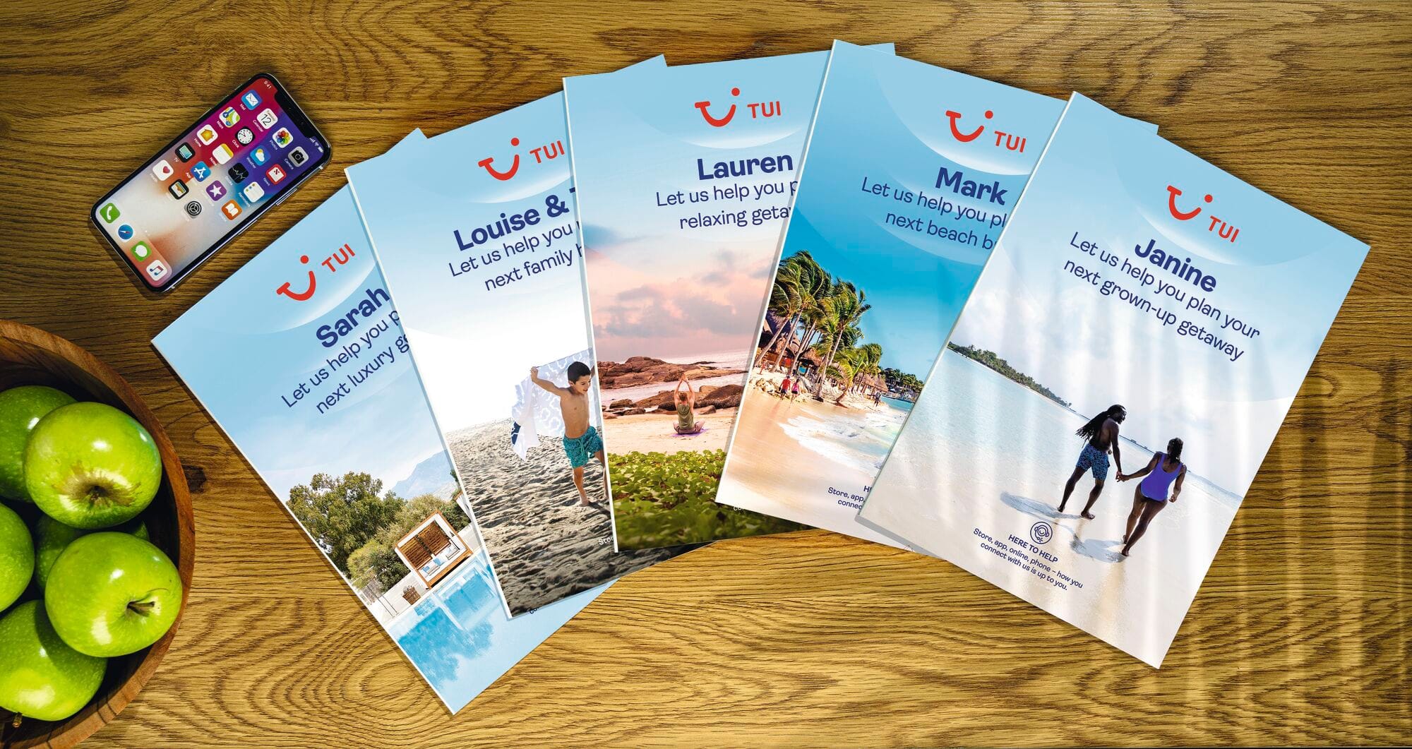 A selection of bespoke brochures fanned out on a wooden table. 