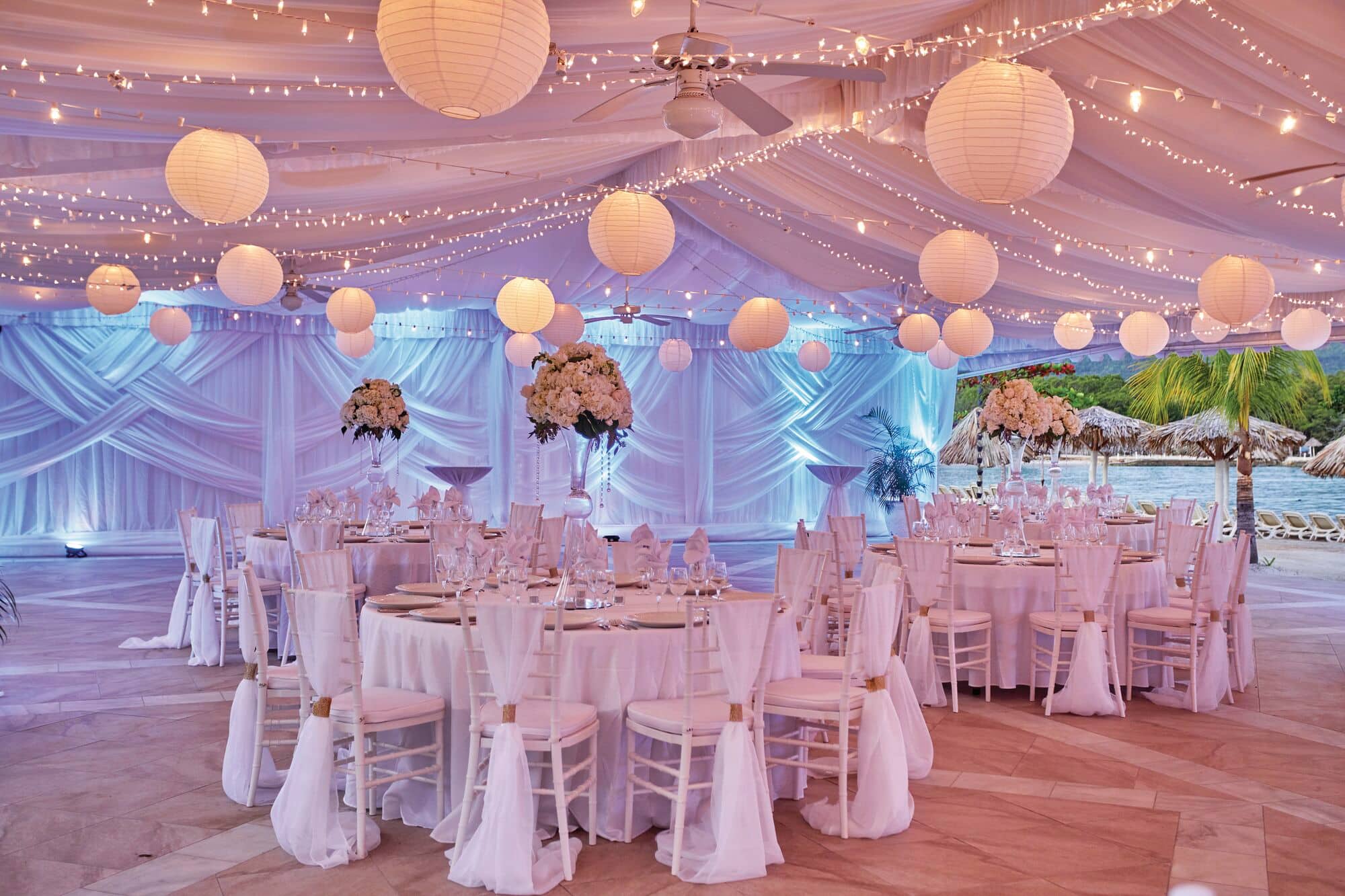 Wedding tables covered in white linens and decorated with floral centrepieces.