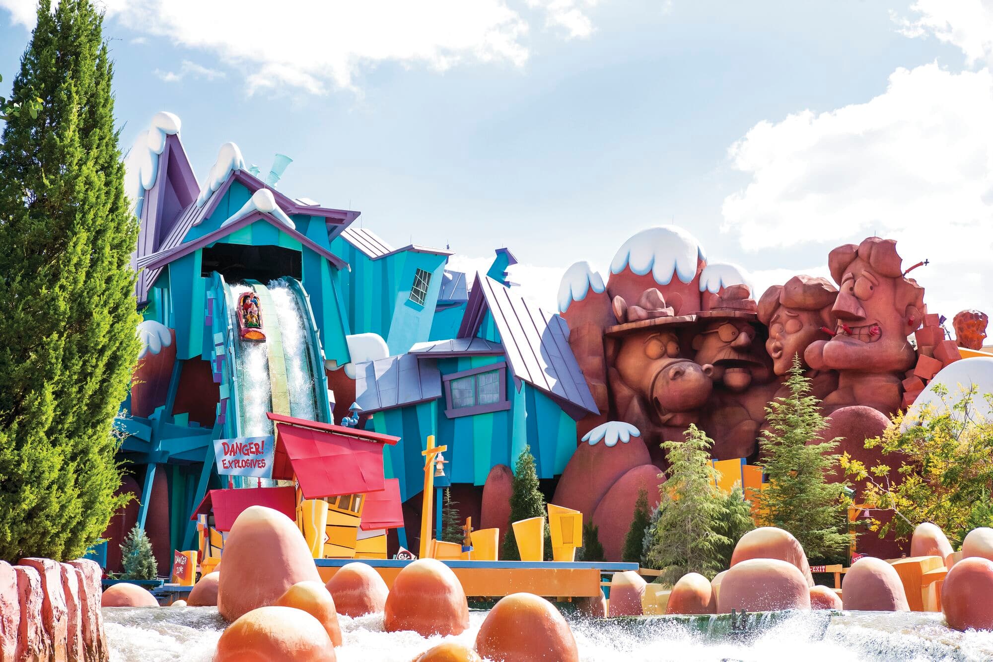 Cartoon-style log flume ride with colourful buildings and a big water splash.