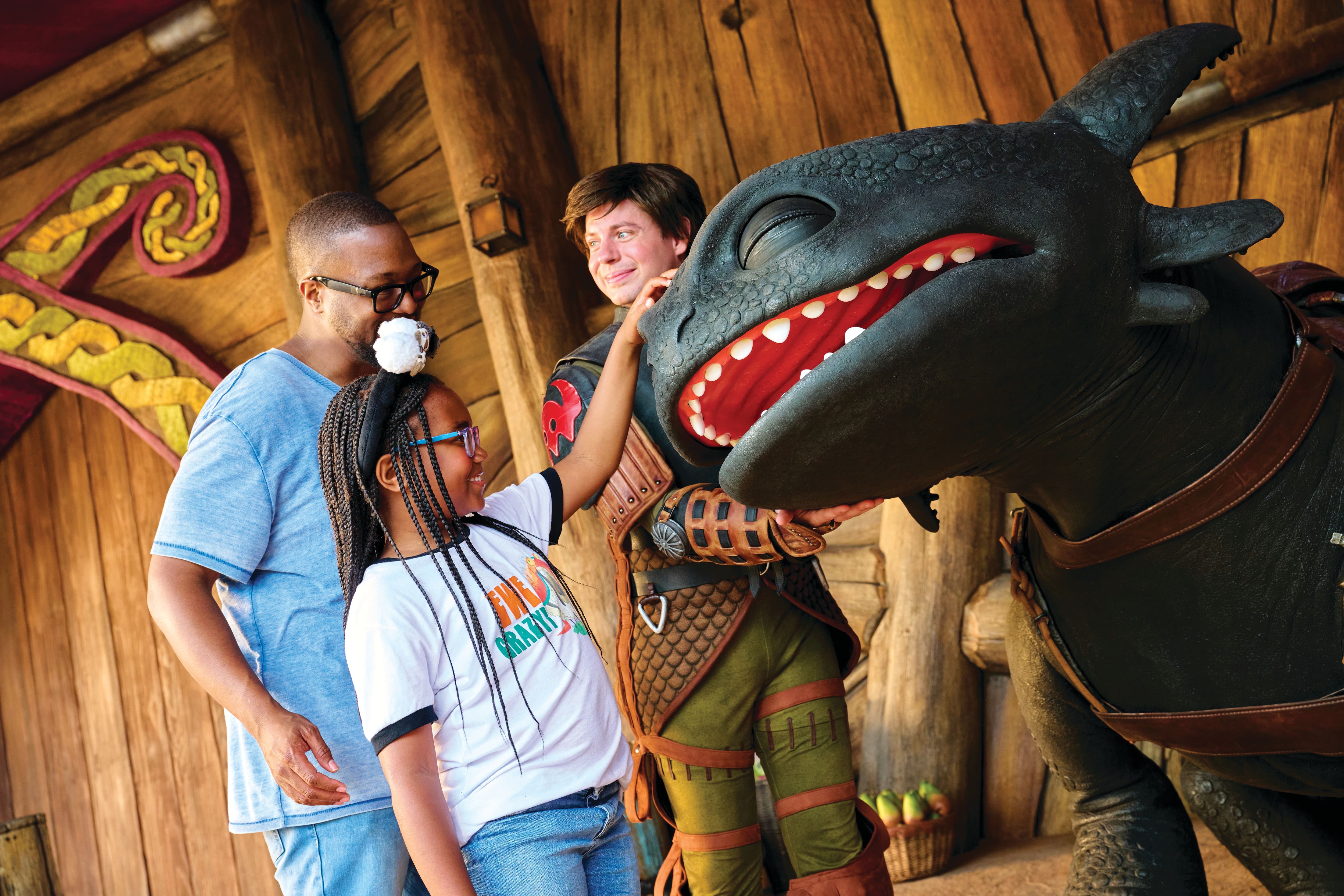 Father and daughter petting a dragon.