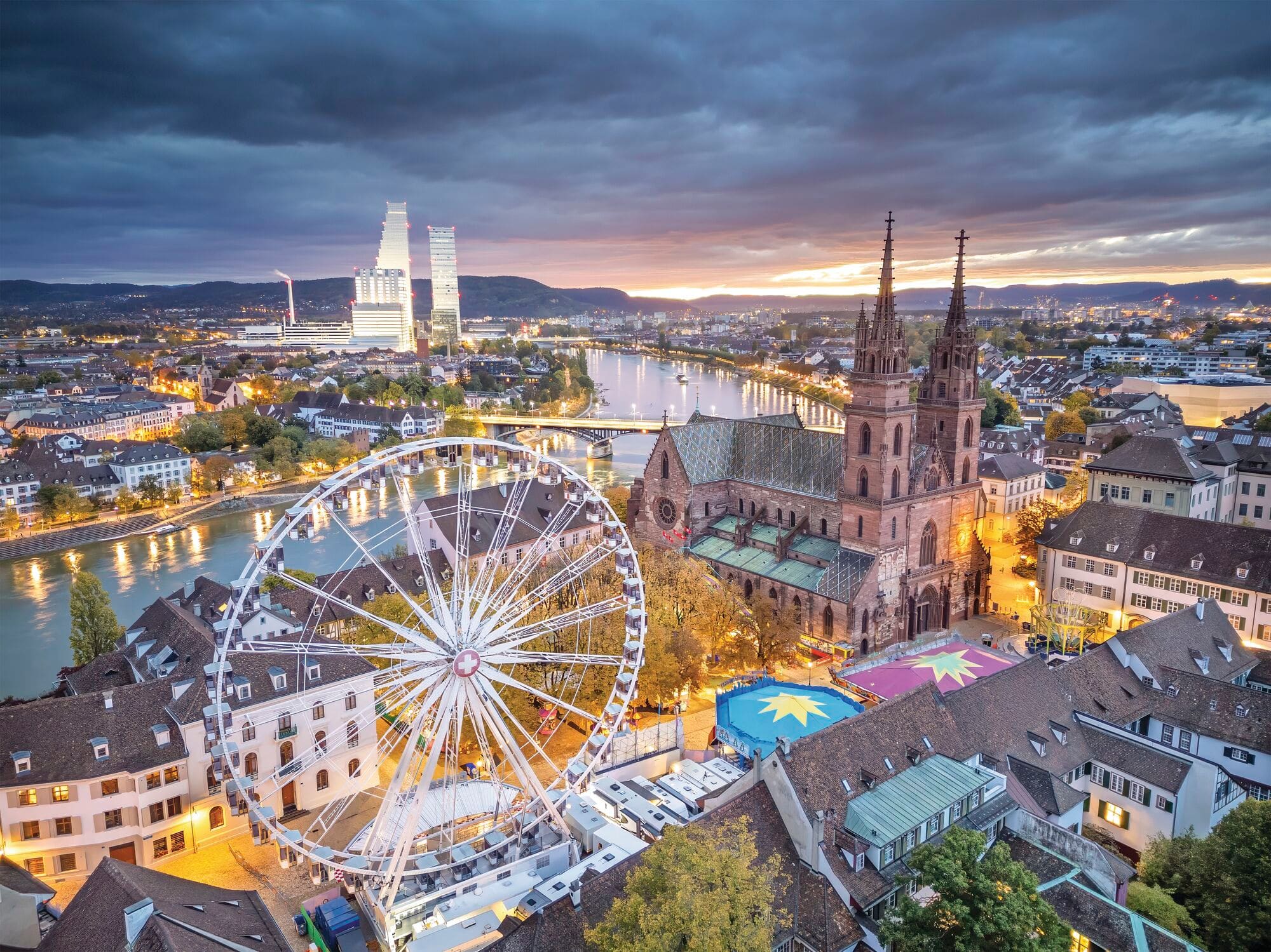 A view over the cathedral and square at night, with a Ferris wheel in the foreground