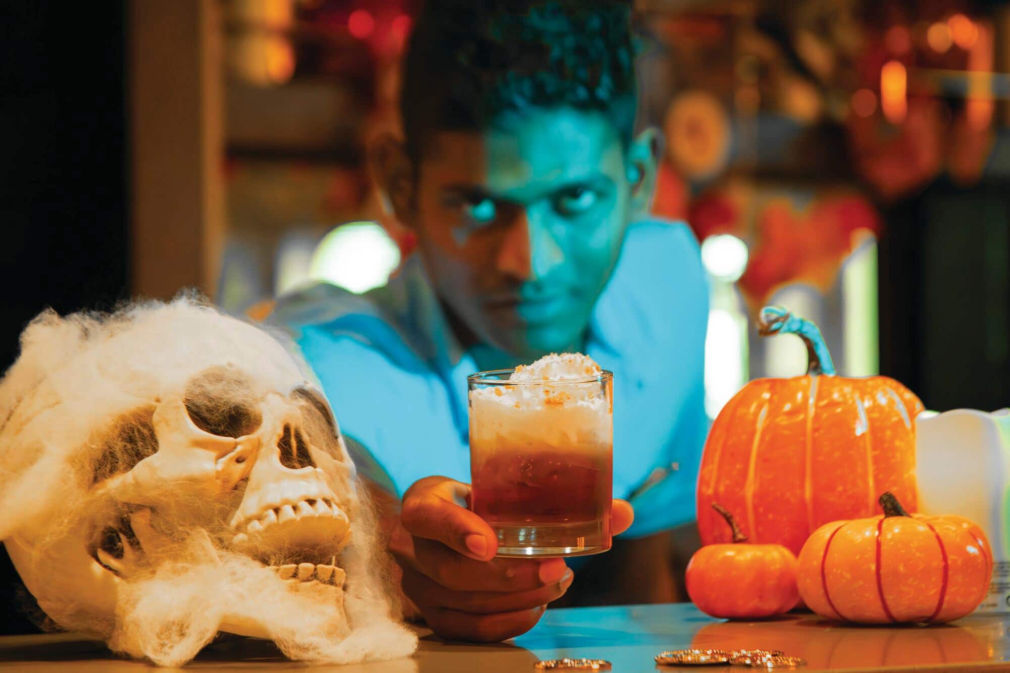 A ar tender serving Halloween themed cocktail.