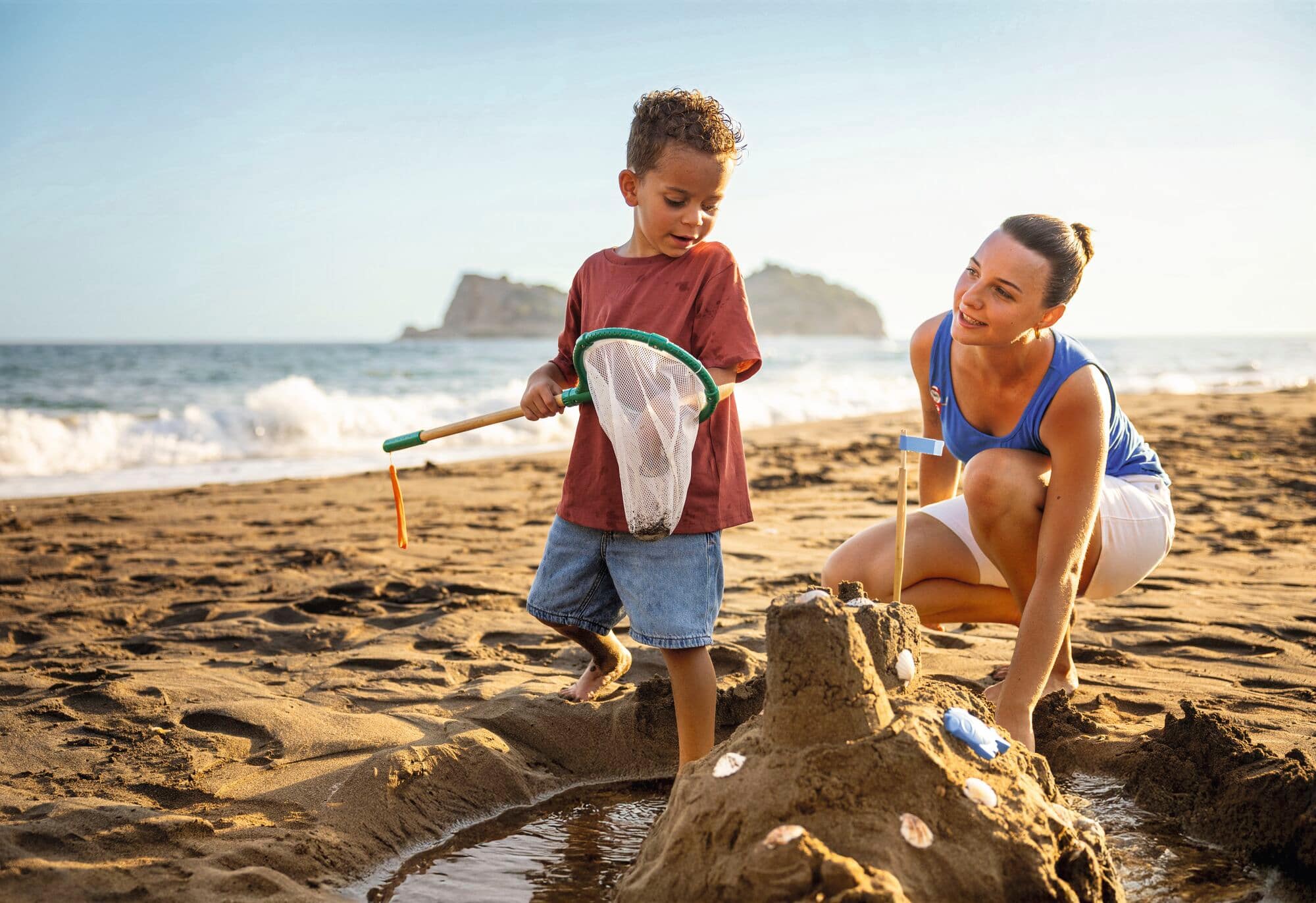 A child and his mother enjoying family time on the beach.