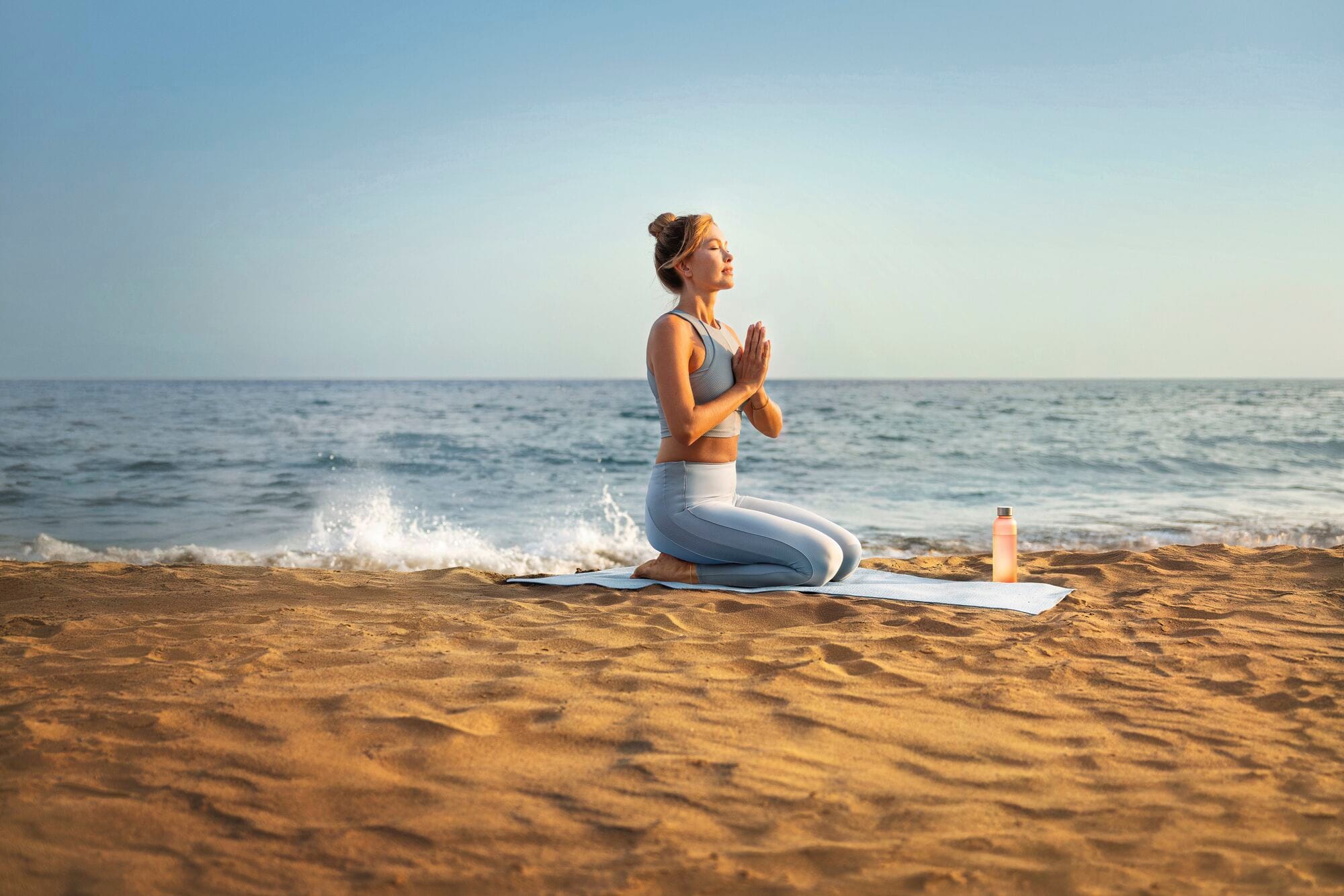 A woman doing yoga on the beach.