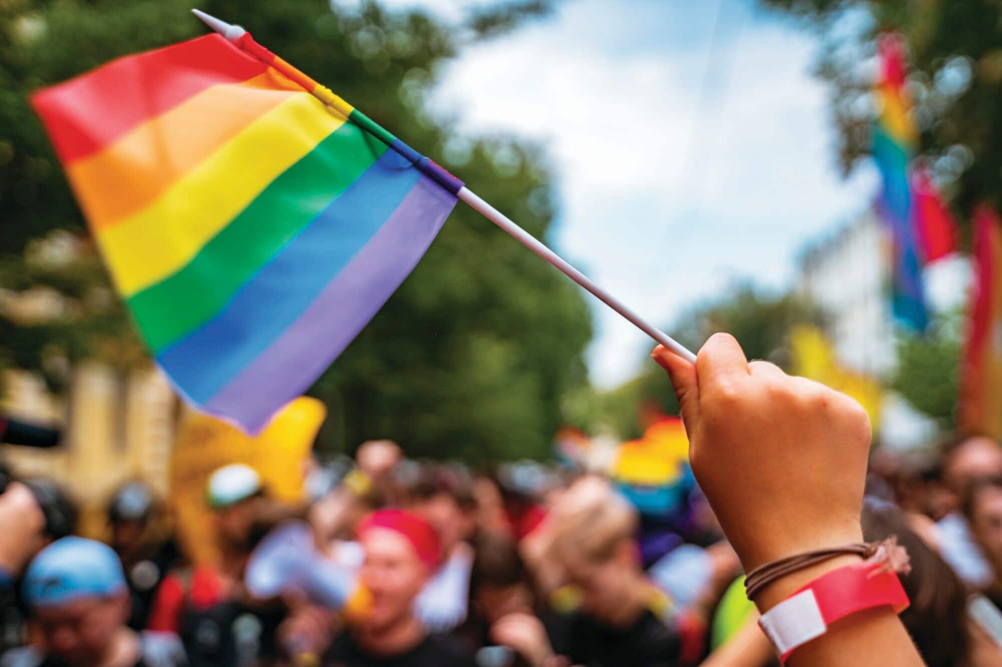 Hand holding a Pride flag.