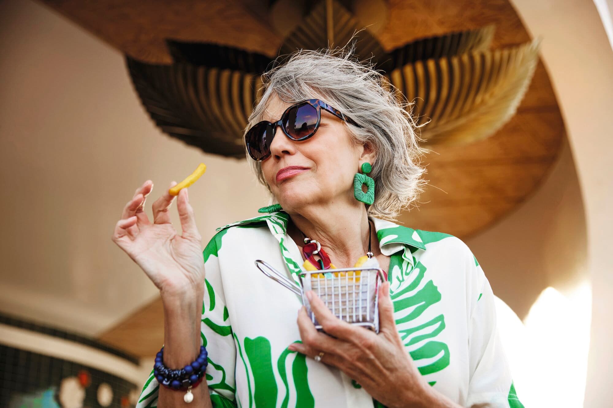A women in colourful clothing eating chips.