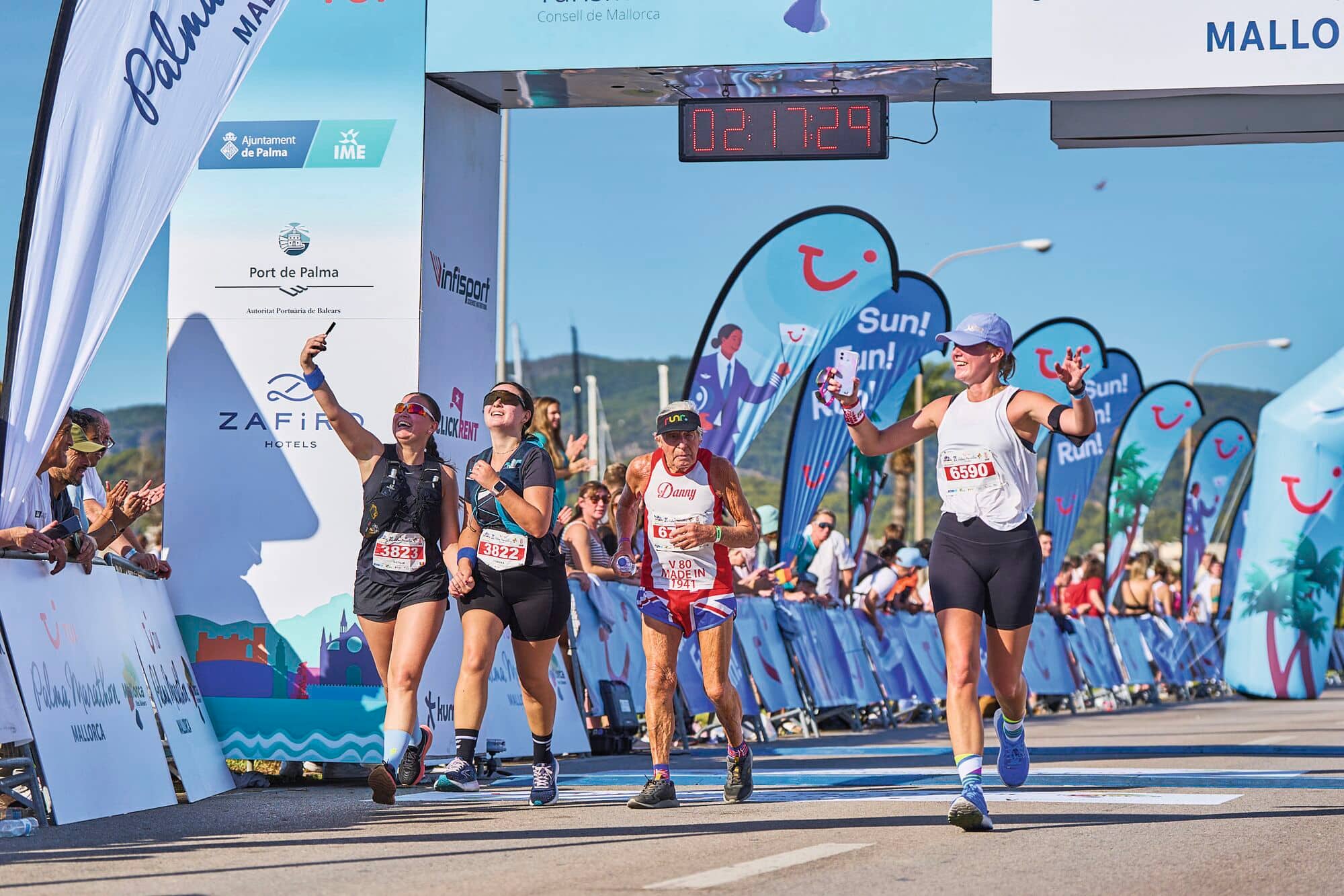 Marathon runners finishing a race in Port de Palma, Mallorca on a sunny day.