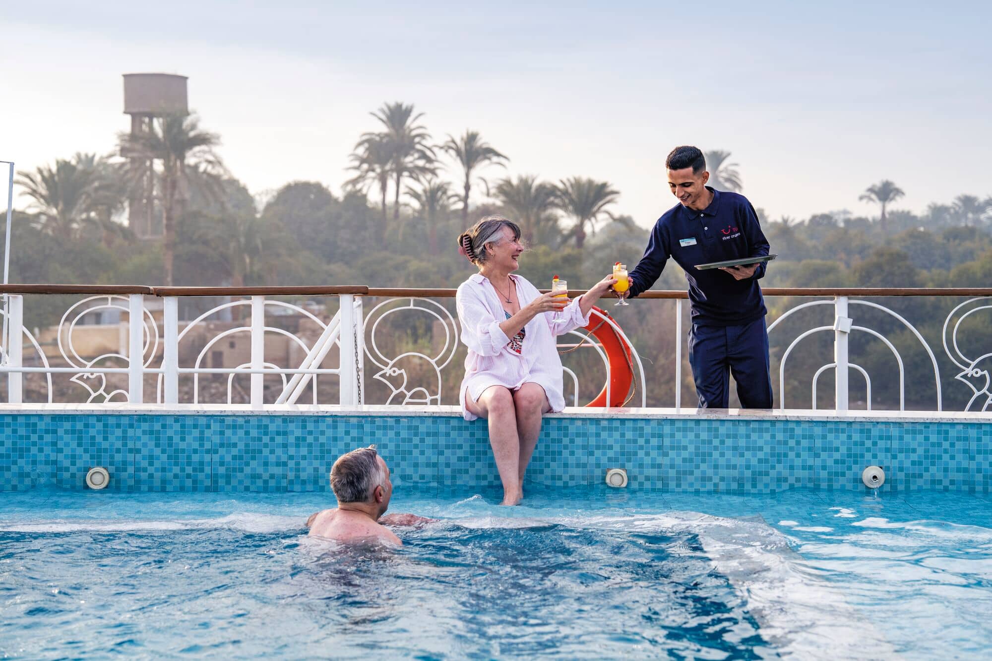 A couple being served drinks at the pool.