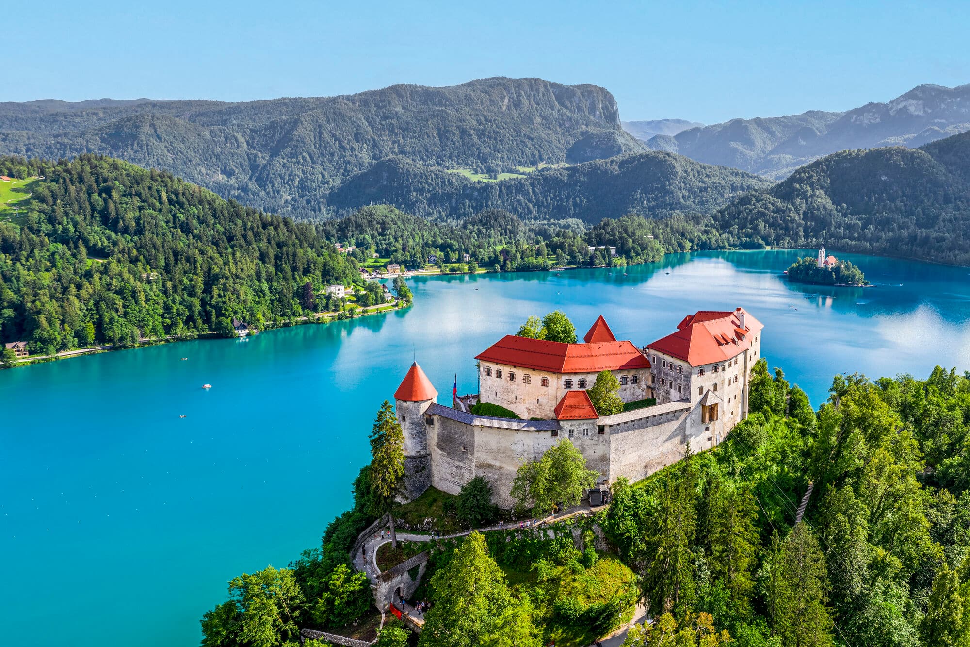 A red-roofed castle on a cliff above Lake Bled in Slovenia.