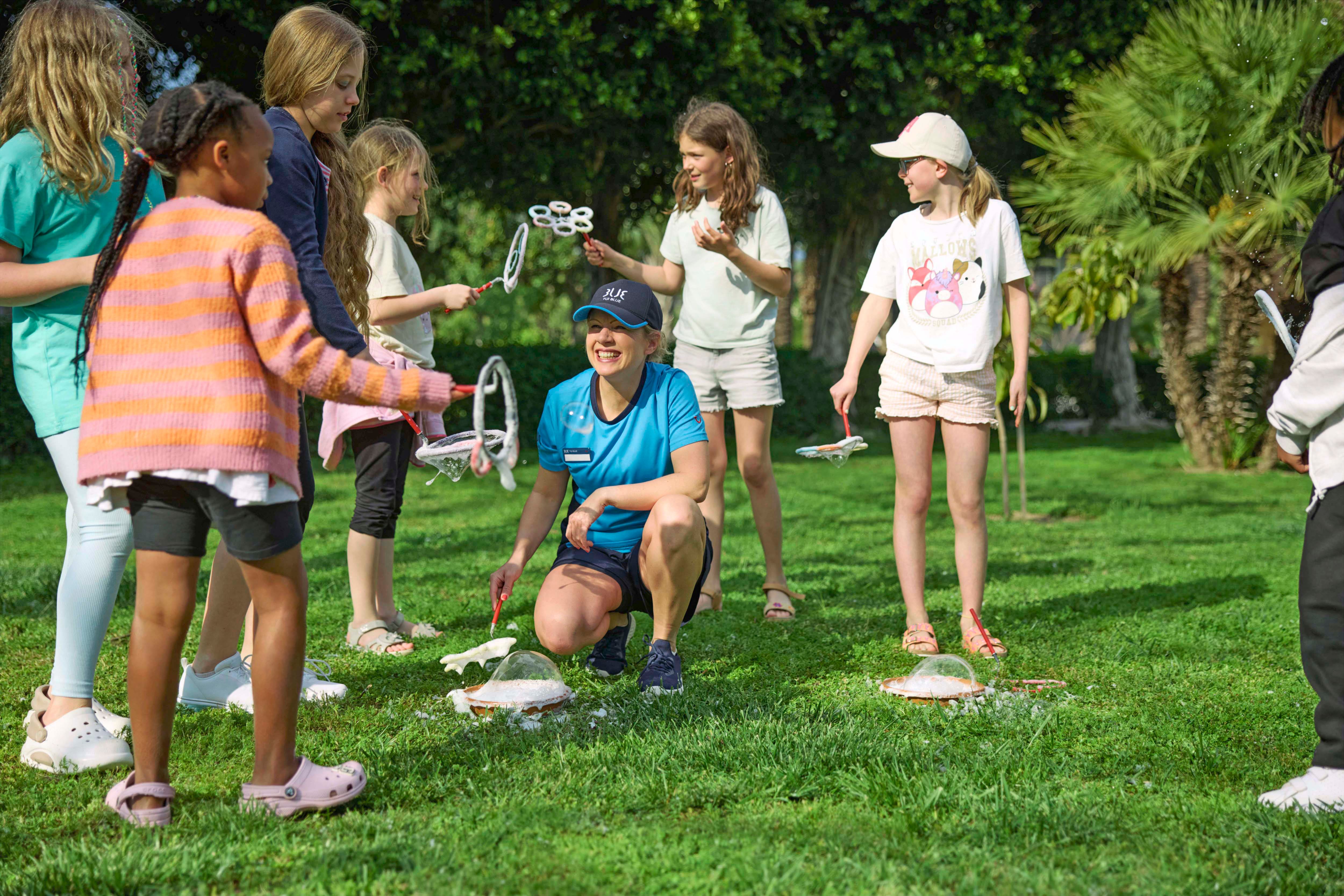A group of children playing with bubbles on green grass.
