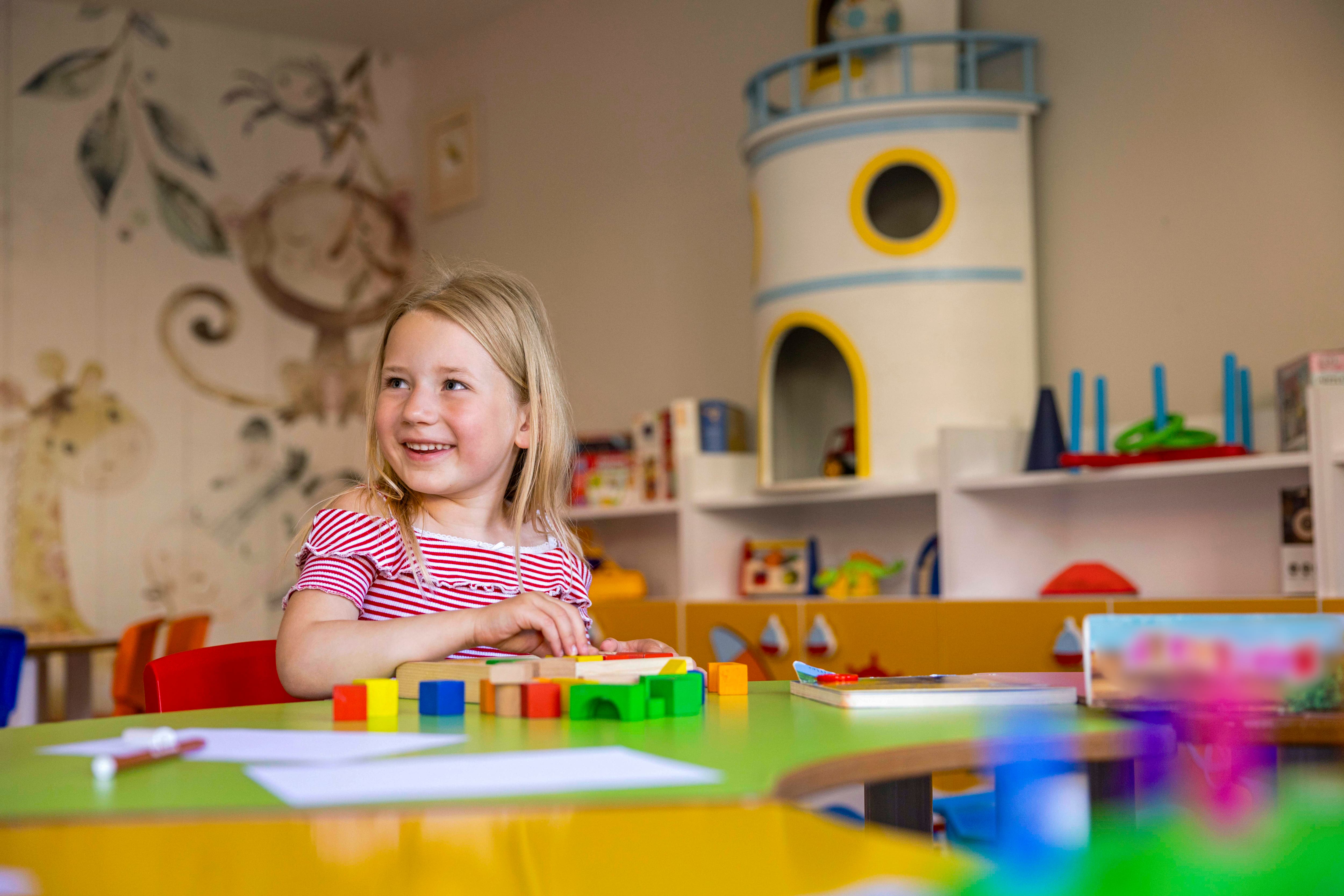Girl playing with blocks in a colourful children's playroom.