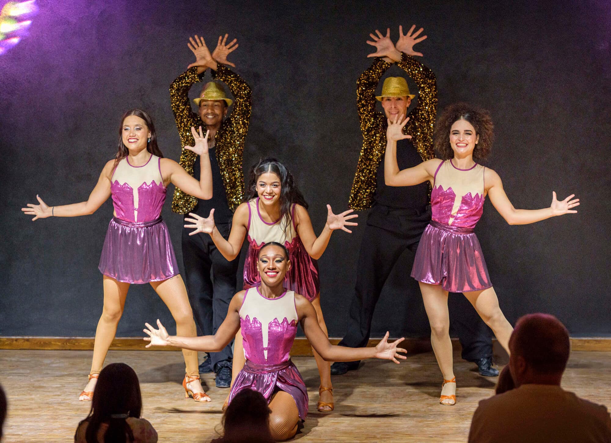 A group of entertainers in bright costumes perform on stage.
