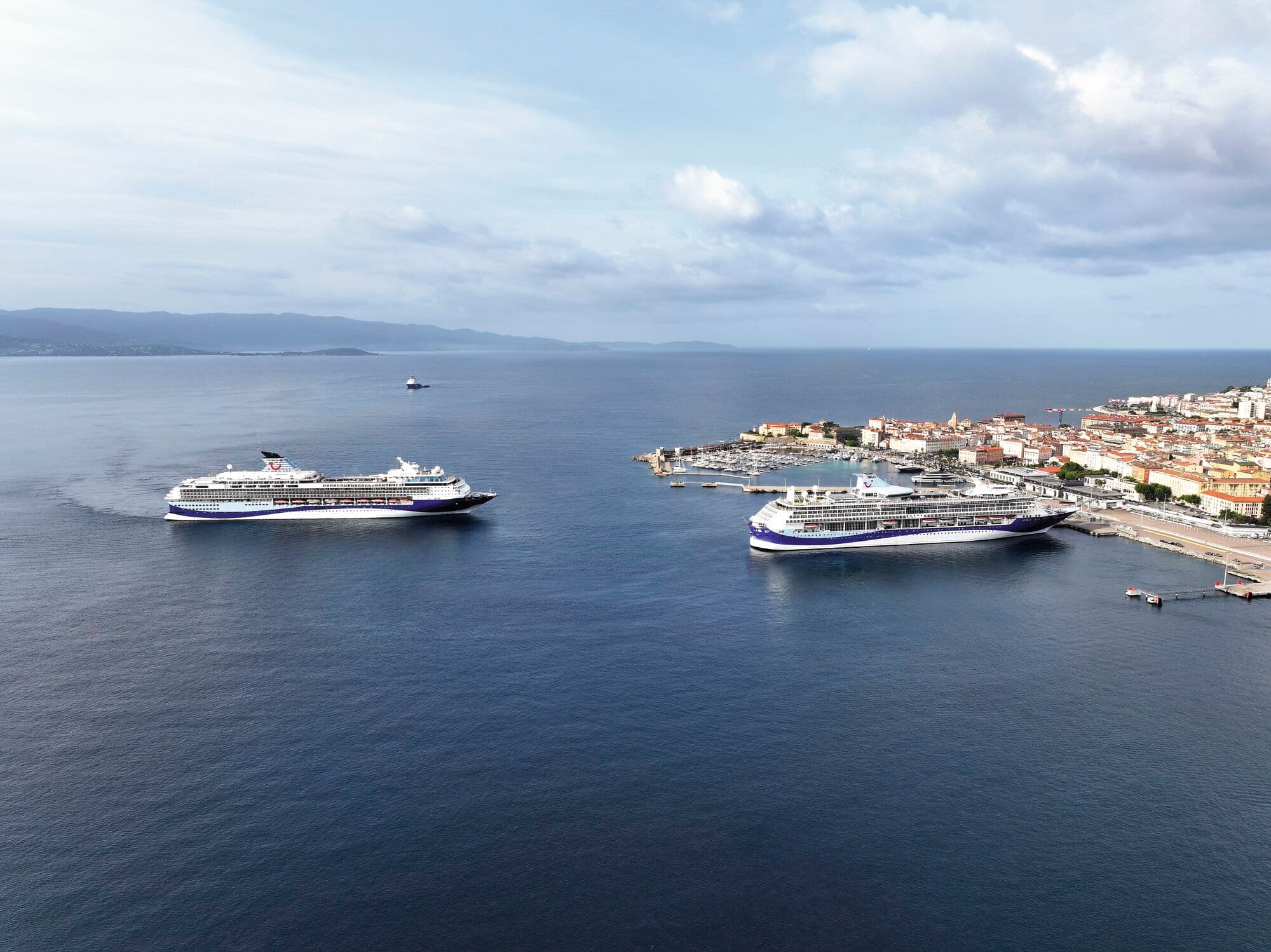 Two cruise ships at sea by a port.