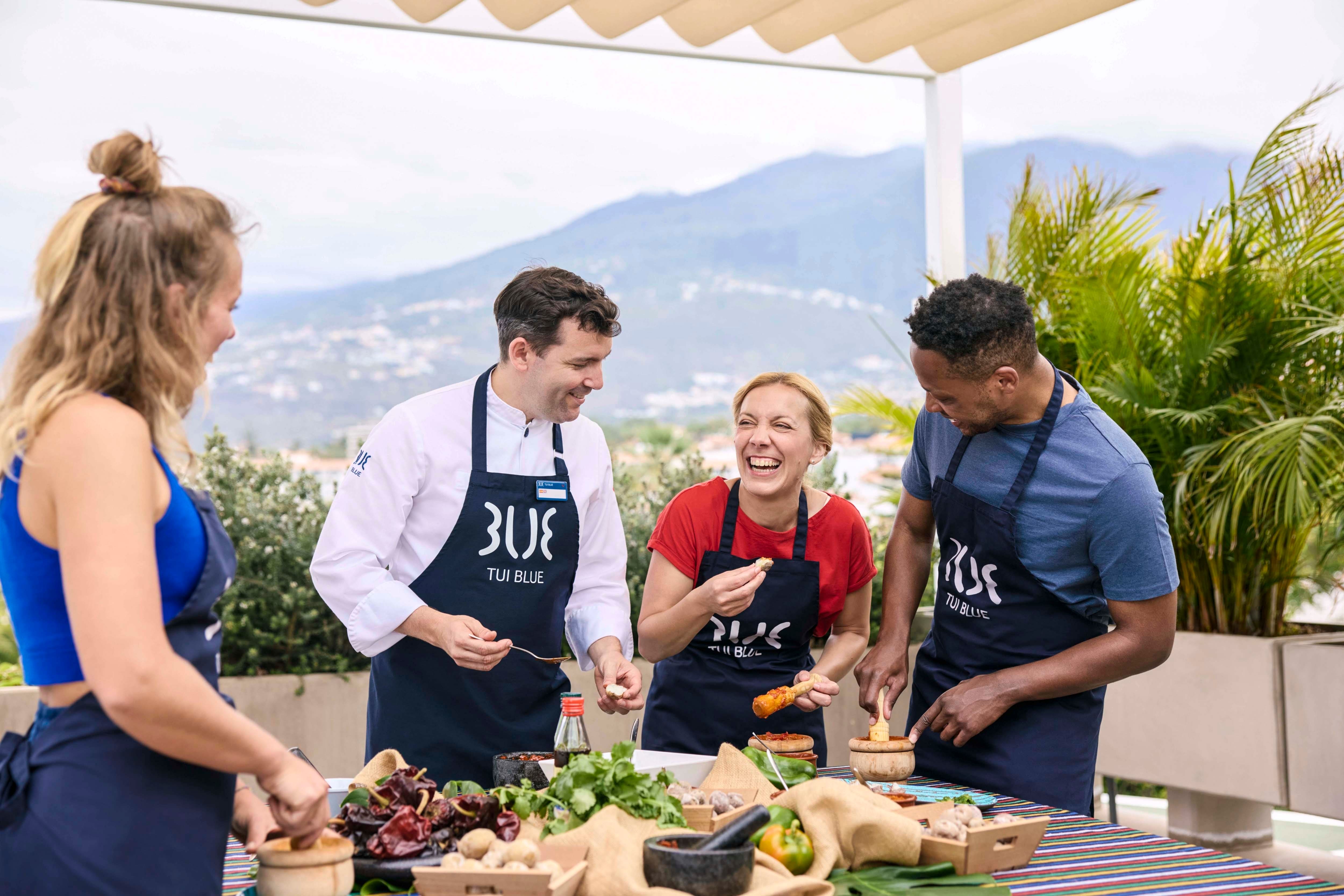 A group of people in TUI Blue aprons taking part in a cooking class.