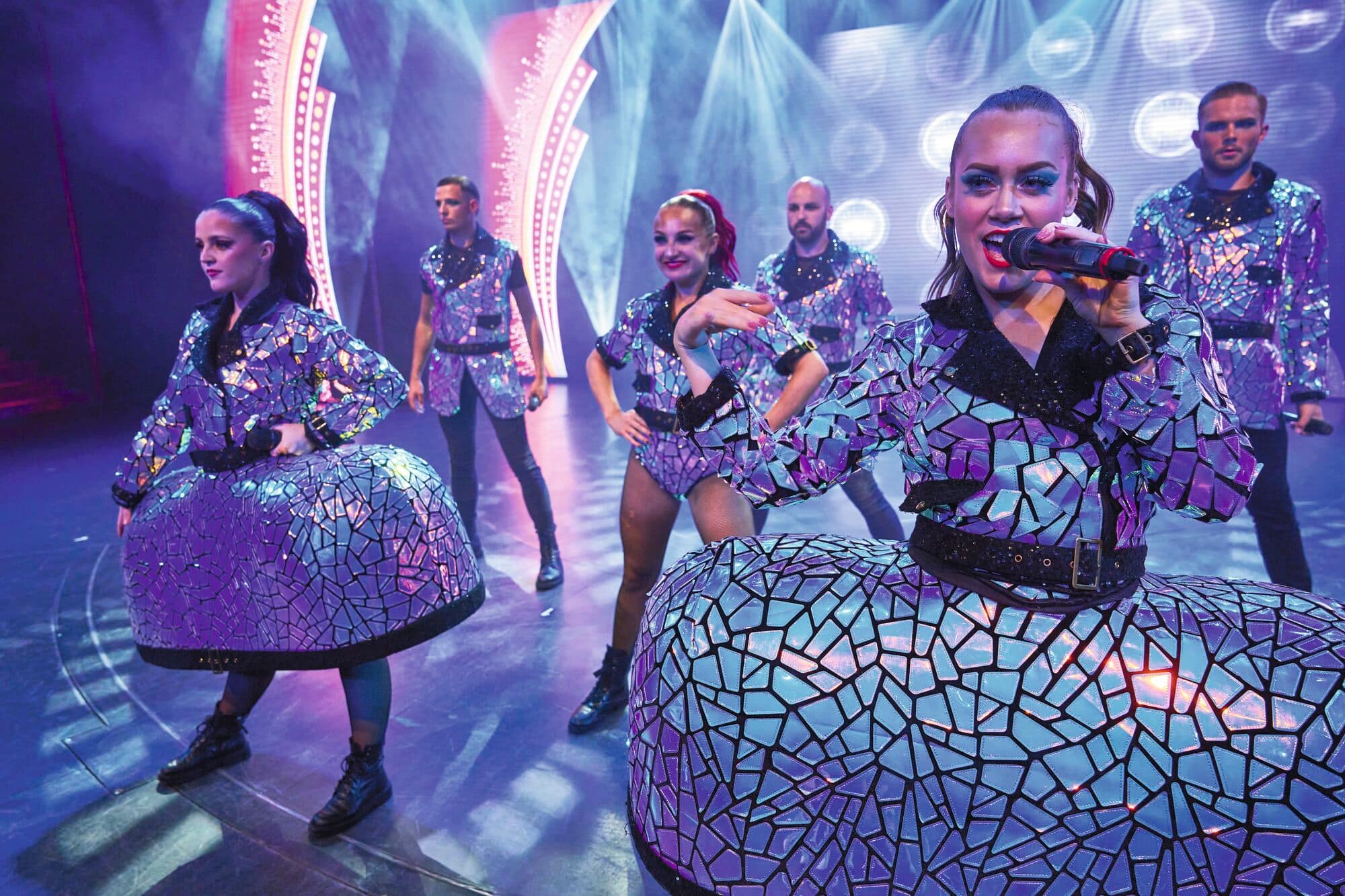 Performers singing and dancing onstage.
