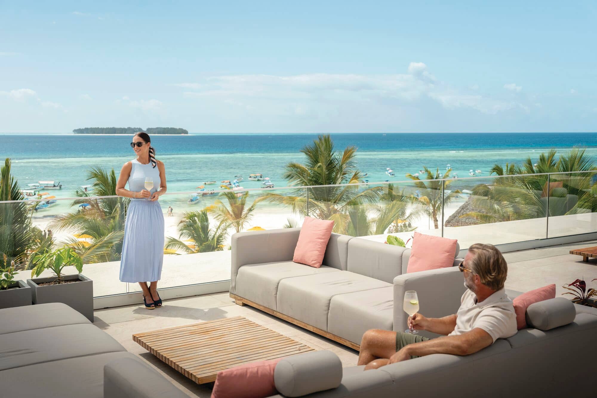 A woman stands against a railing with a small island in the background.