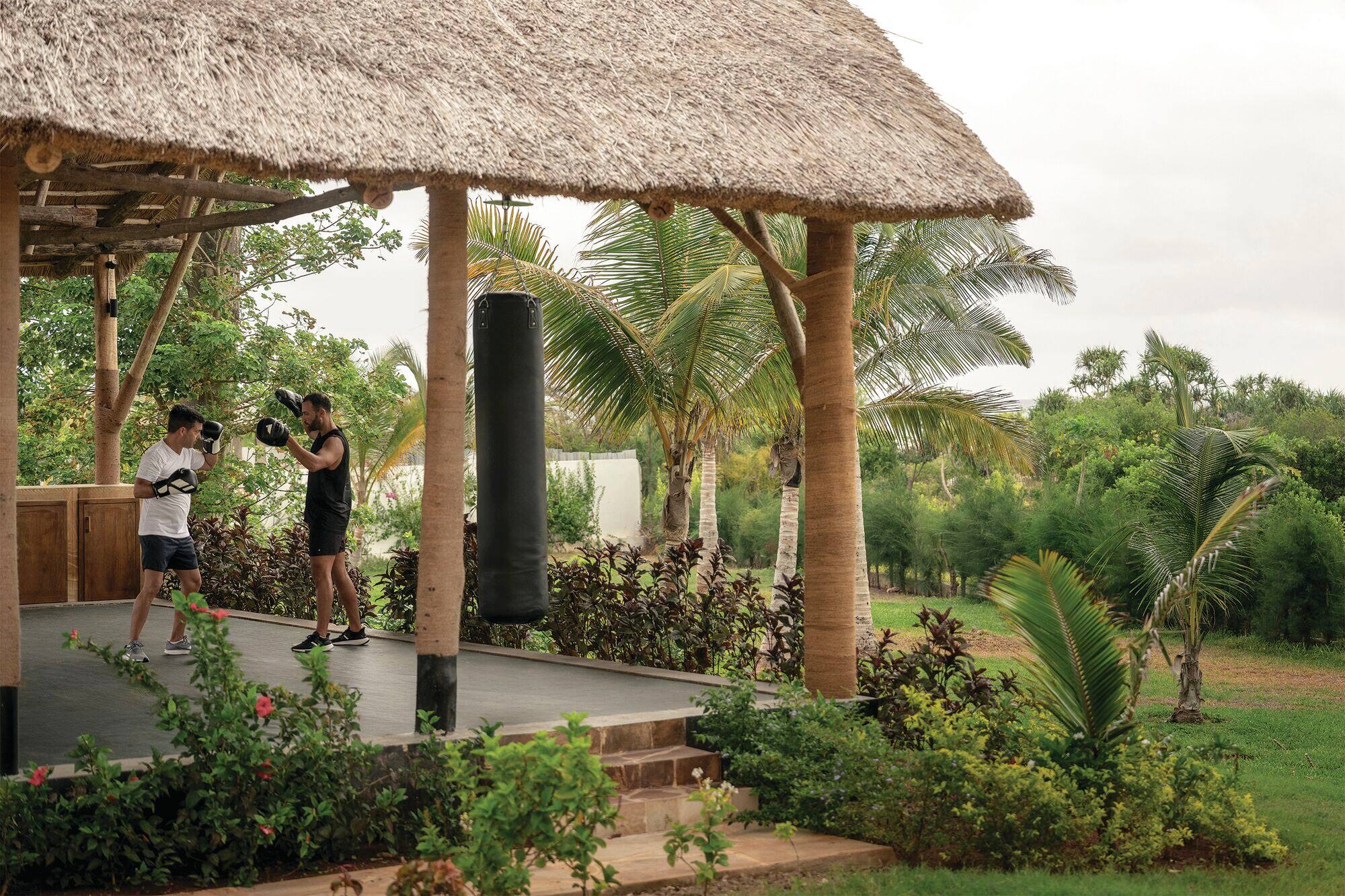 Two men practice boxing in an outdoor sports area.