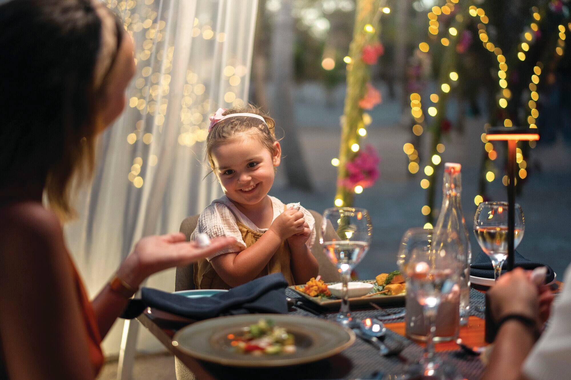 A young girl smiles as she compares seashells with her mother.