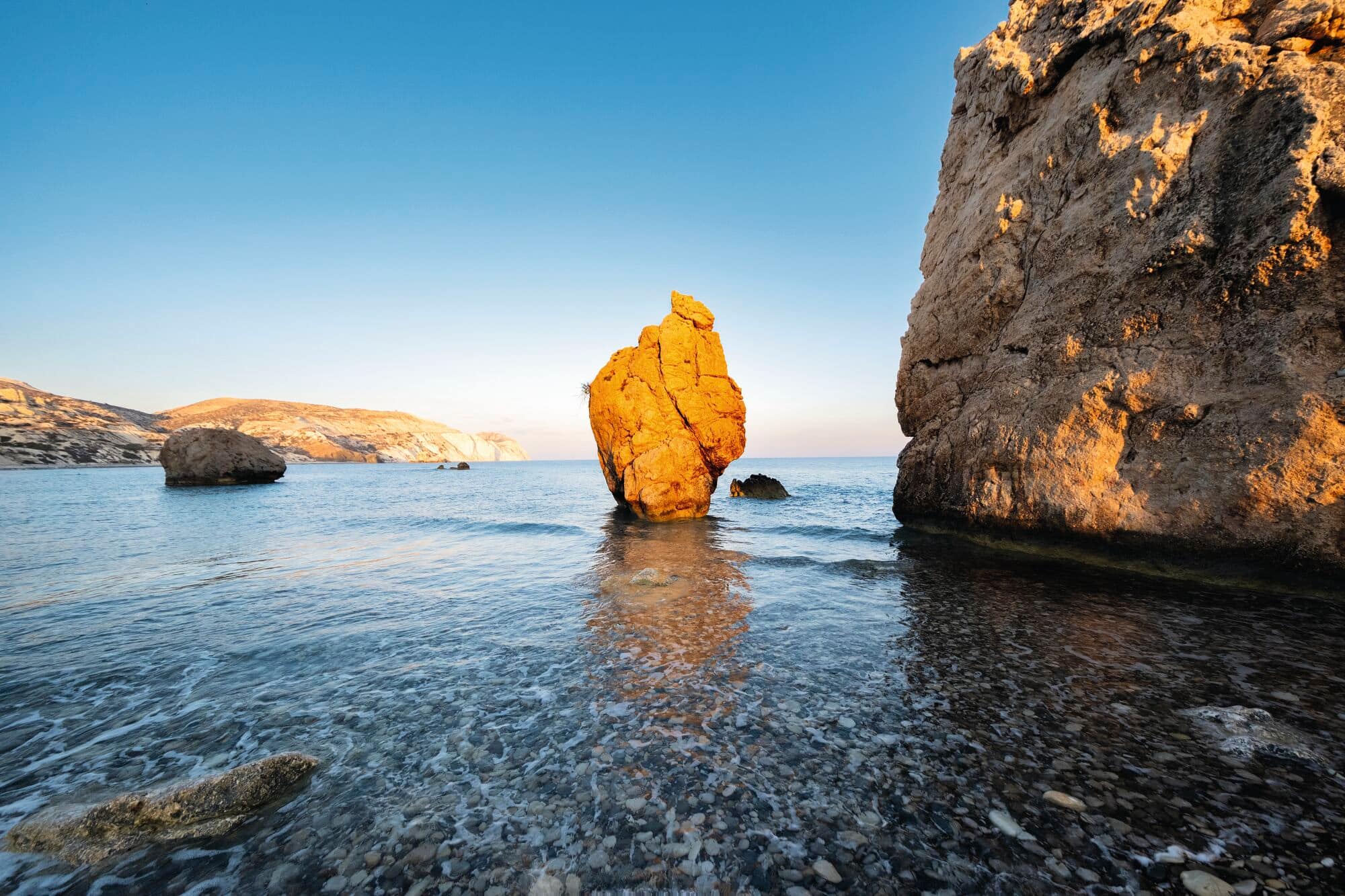 Sun shining on rock formations in the sea.
