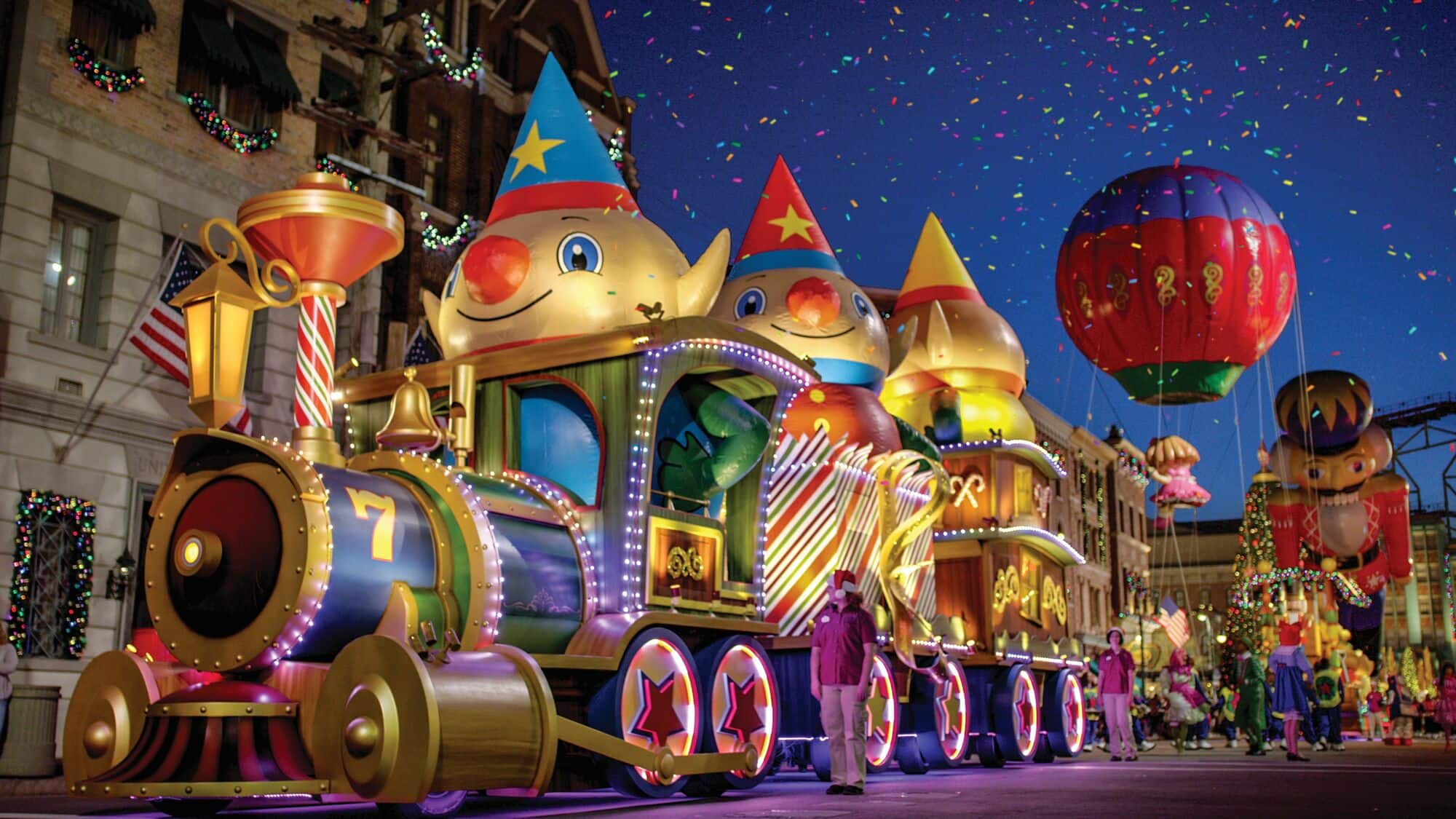 A Christmas themed train with giant elf heads poking out of the top.