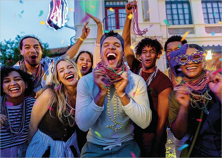 A group of people celebrating and wearing colourful clothing and masks.