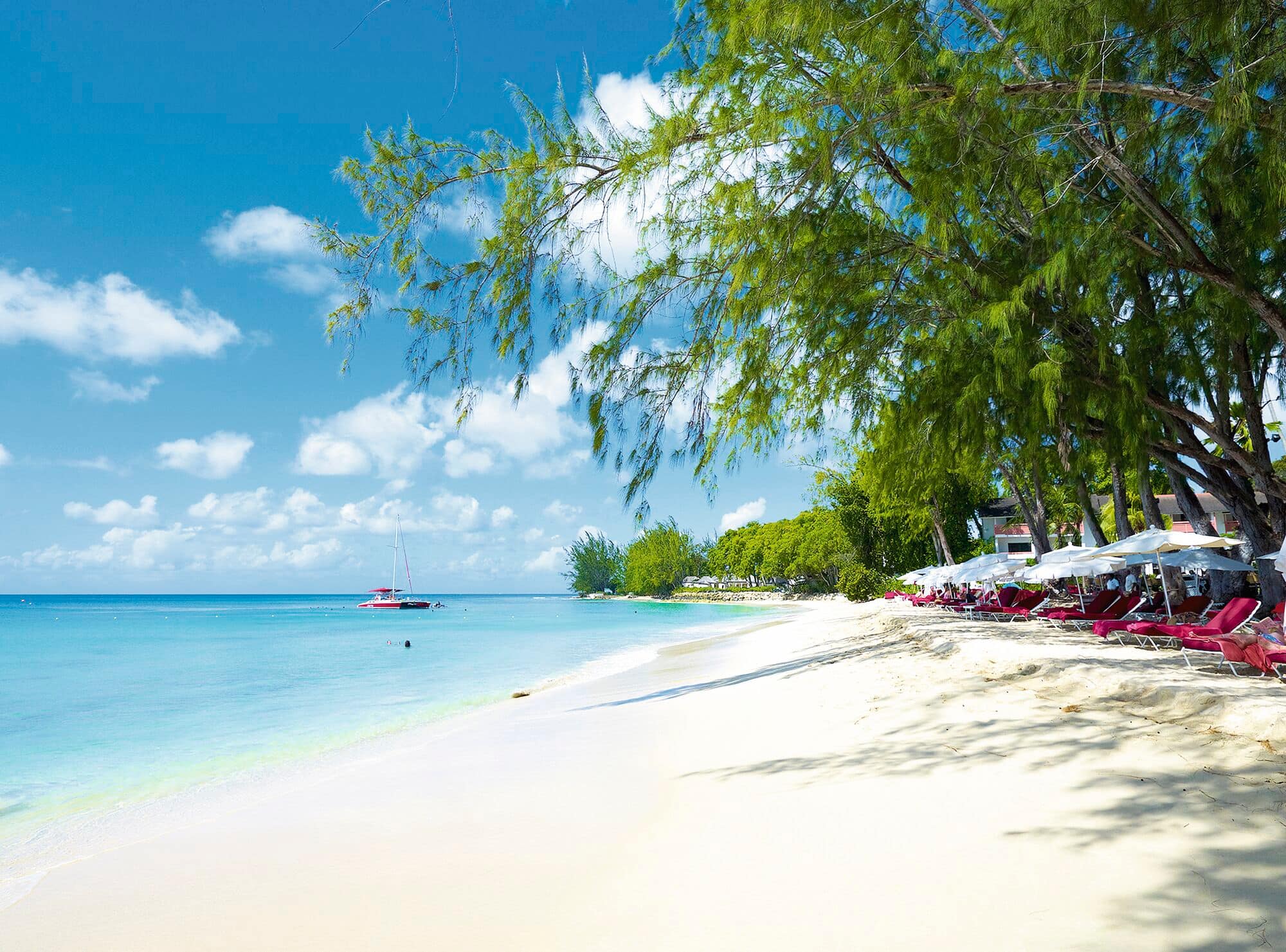 A sandy beach with yachts in the sea.
