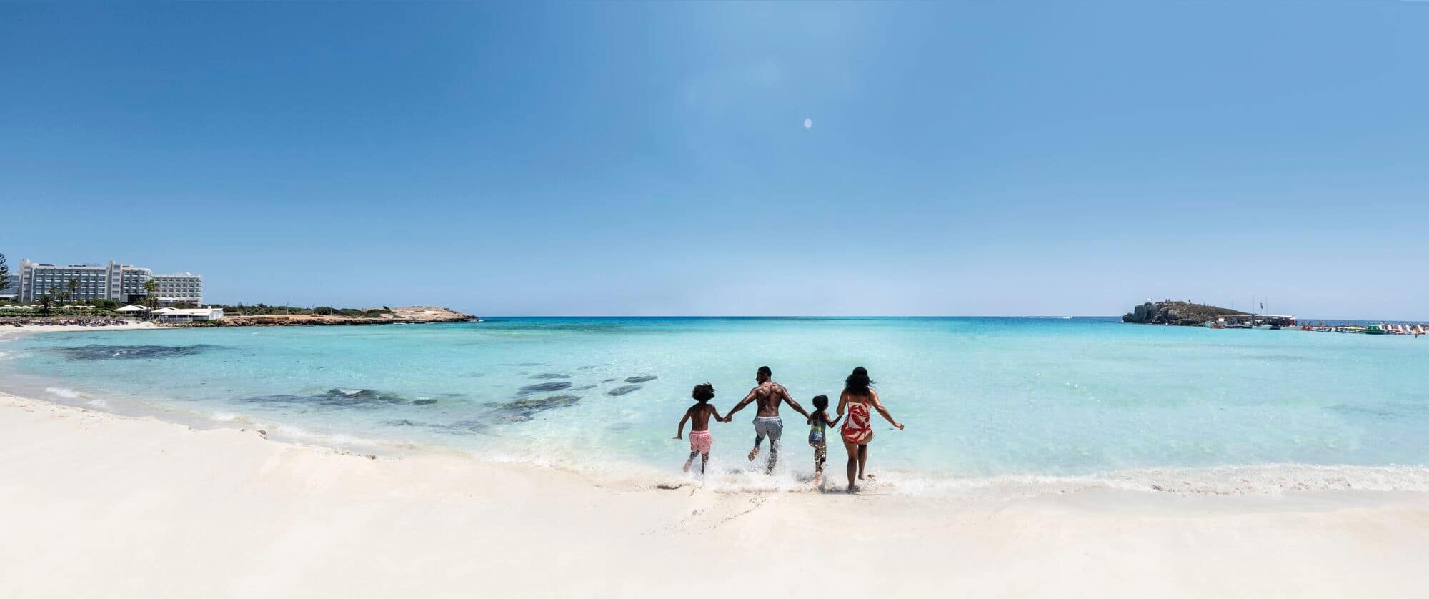 A family running in the sea at Nissi beach, Cyprus.