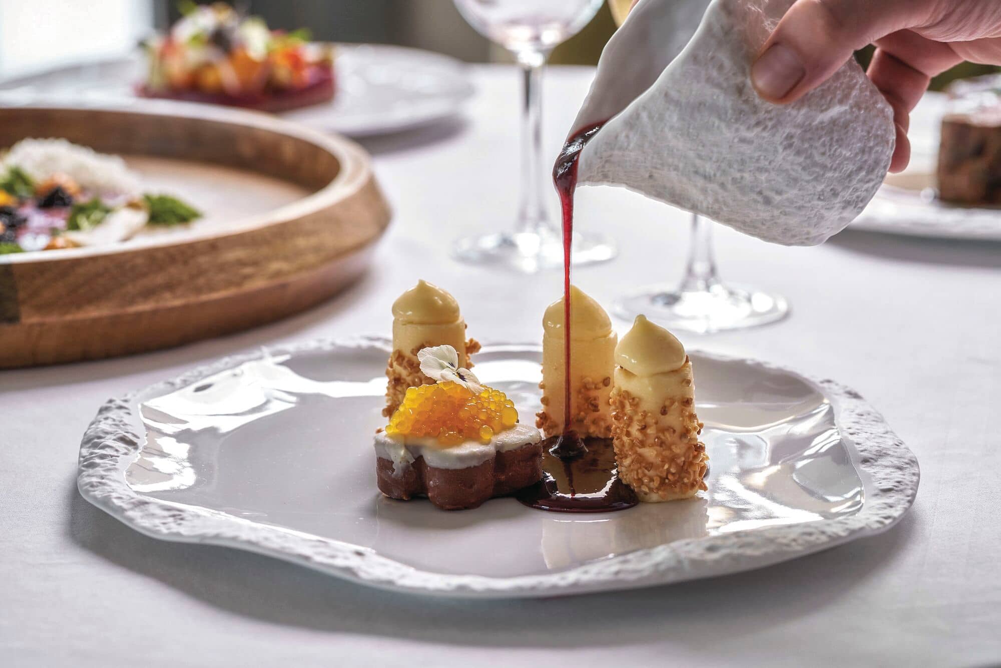 Raspberry sauce being poured over a dessert.