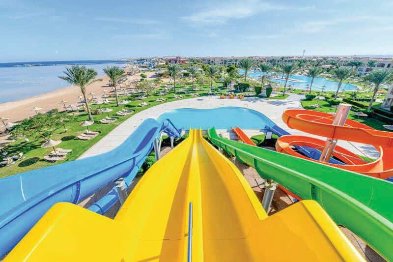 A view from the top of a water slide looks over a sunny resort.
