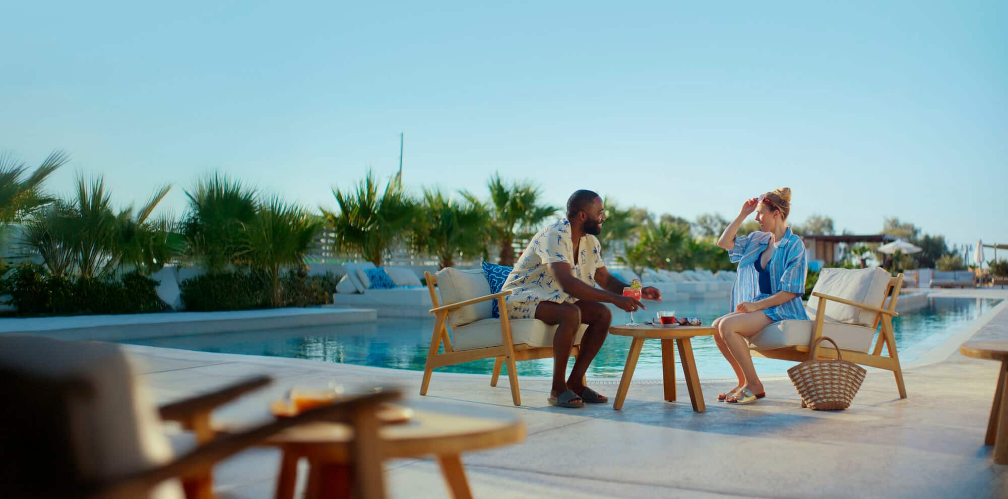 MAFS couples sitting by a pool with a cocktail.