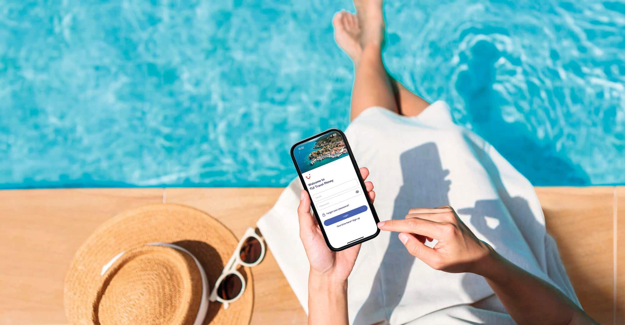 A person by a pool using a smart phone displaying the TUI Travel Money app page.