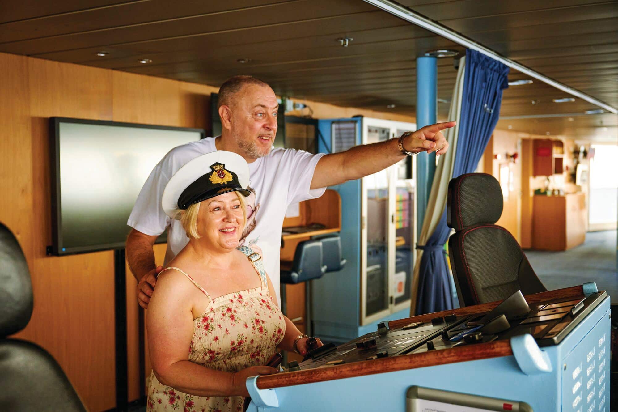 Tracey and Mark on the bridge of the ship. Tracey is wearing a captain's hat.